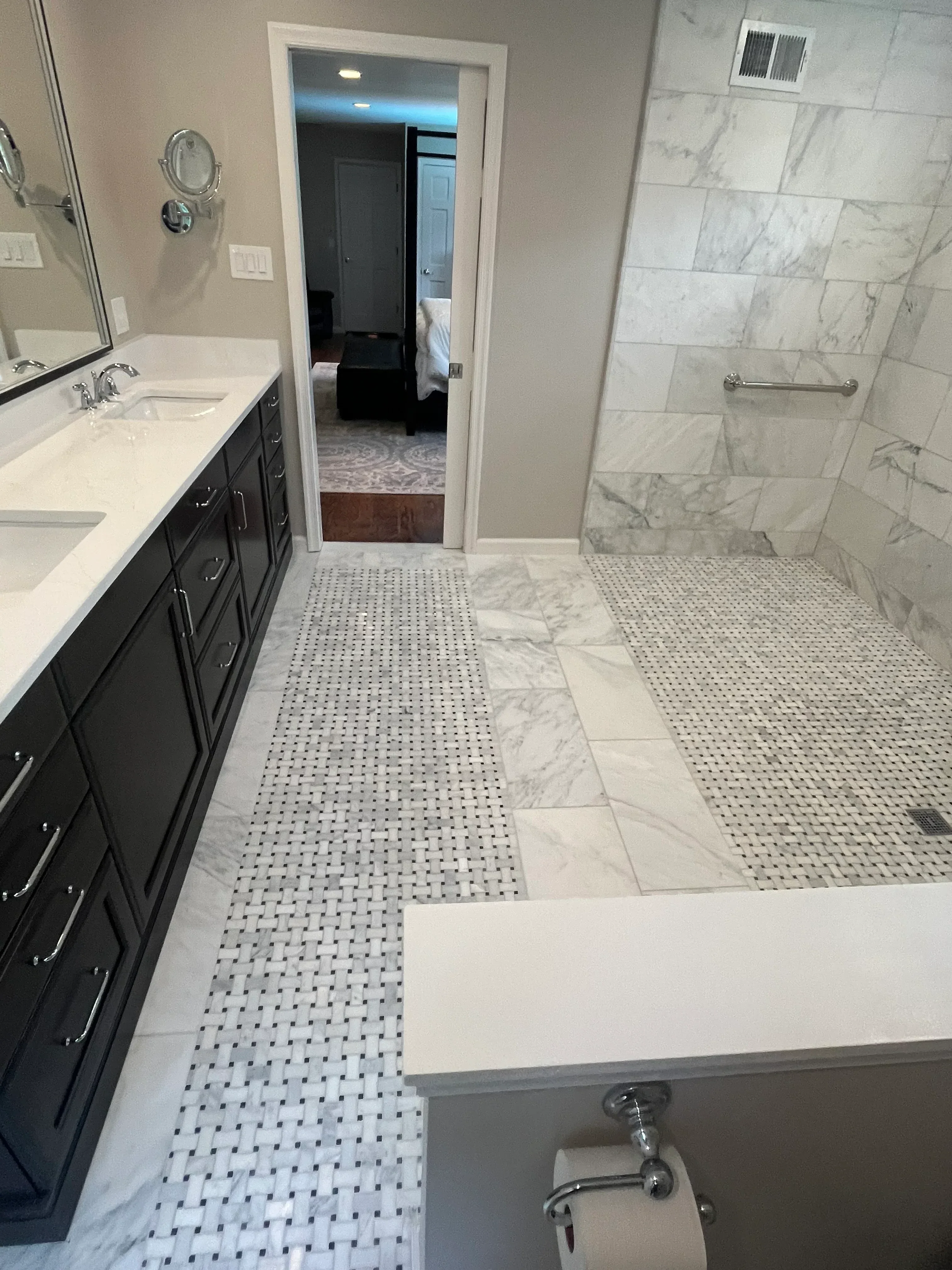 Bathroom with marble tile walls, penny-round mosaic accents, frameless glass shower enclosure, and black fixtures