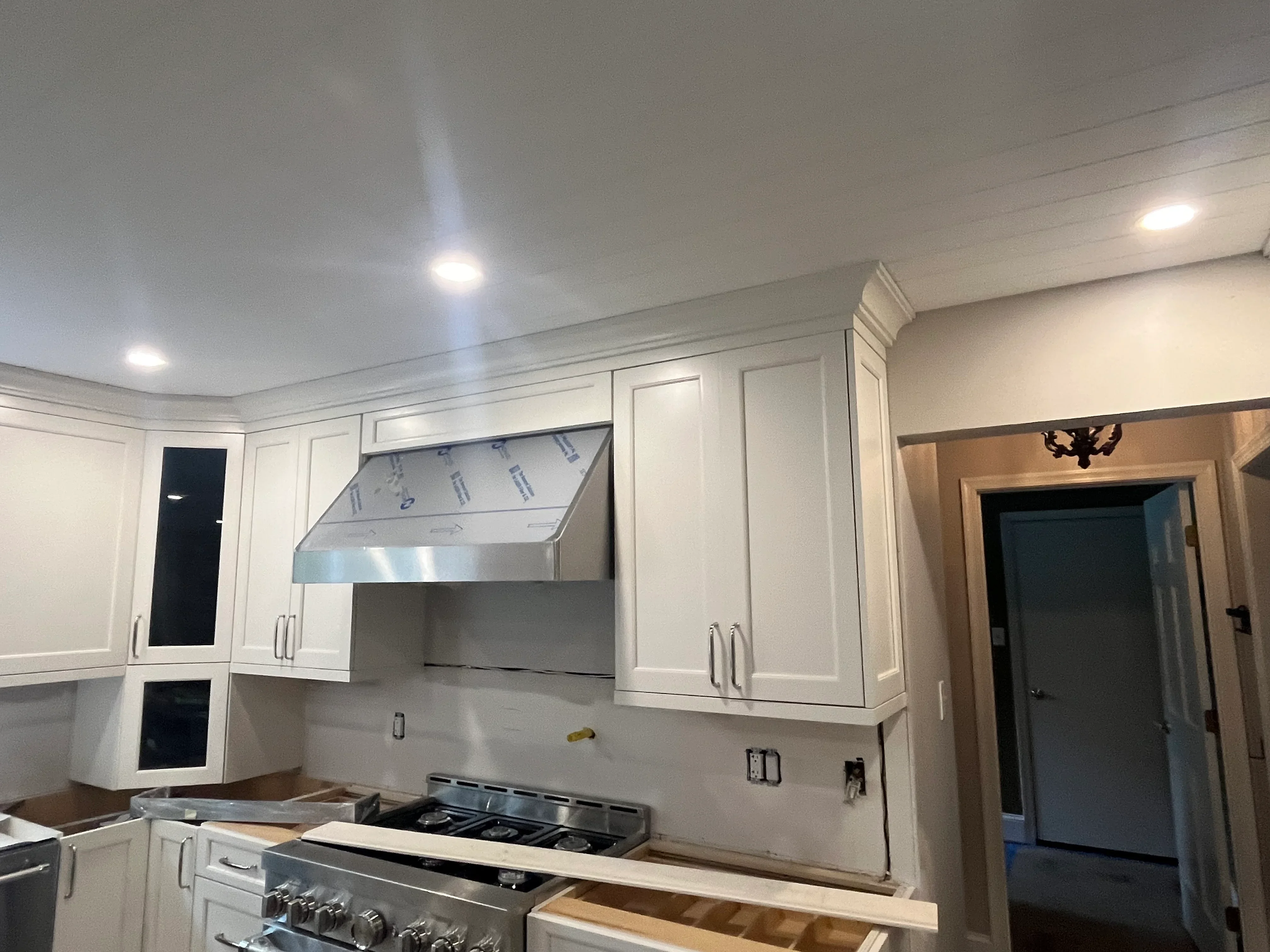 White kitchen cabinets with stainless steel range hood and gas cooktop installation