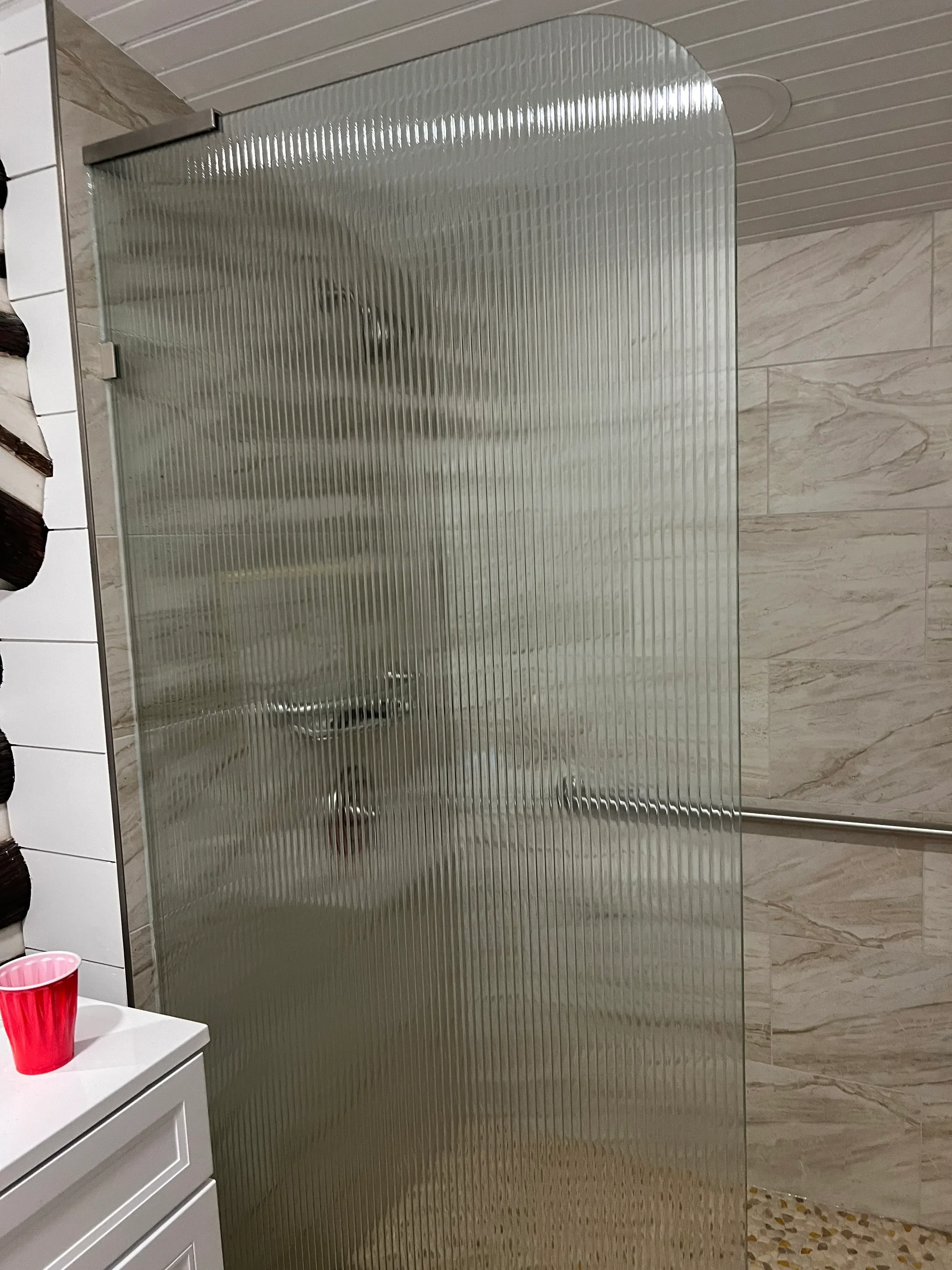 Frameless glass shower enclosure with textured panels and chrome hardware in bathroom