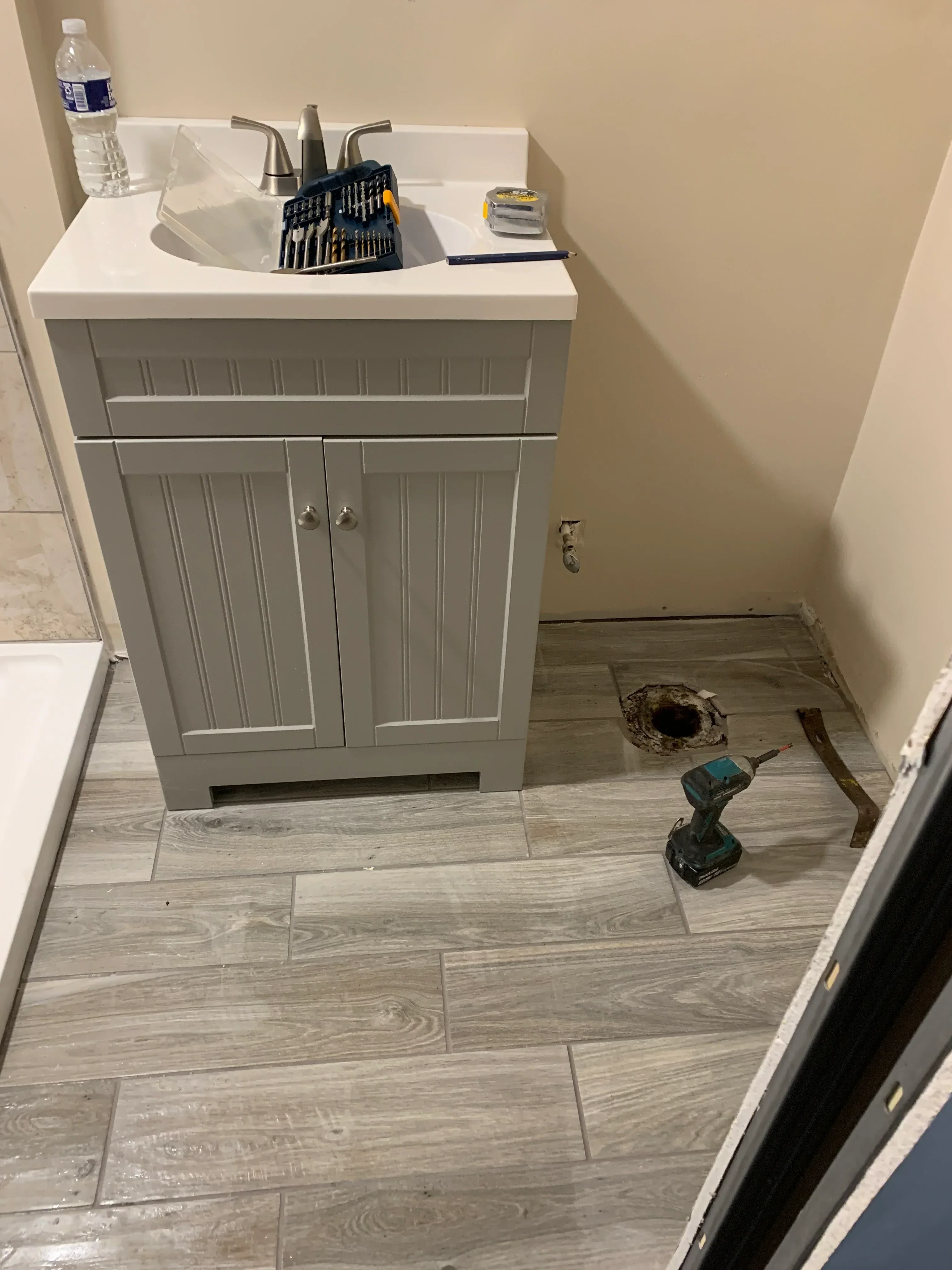 Gray bathroom vanity with horizontal panels and gray wood-look tile walls and flooring