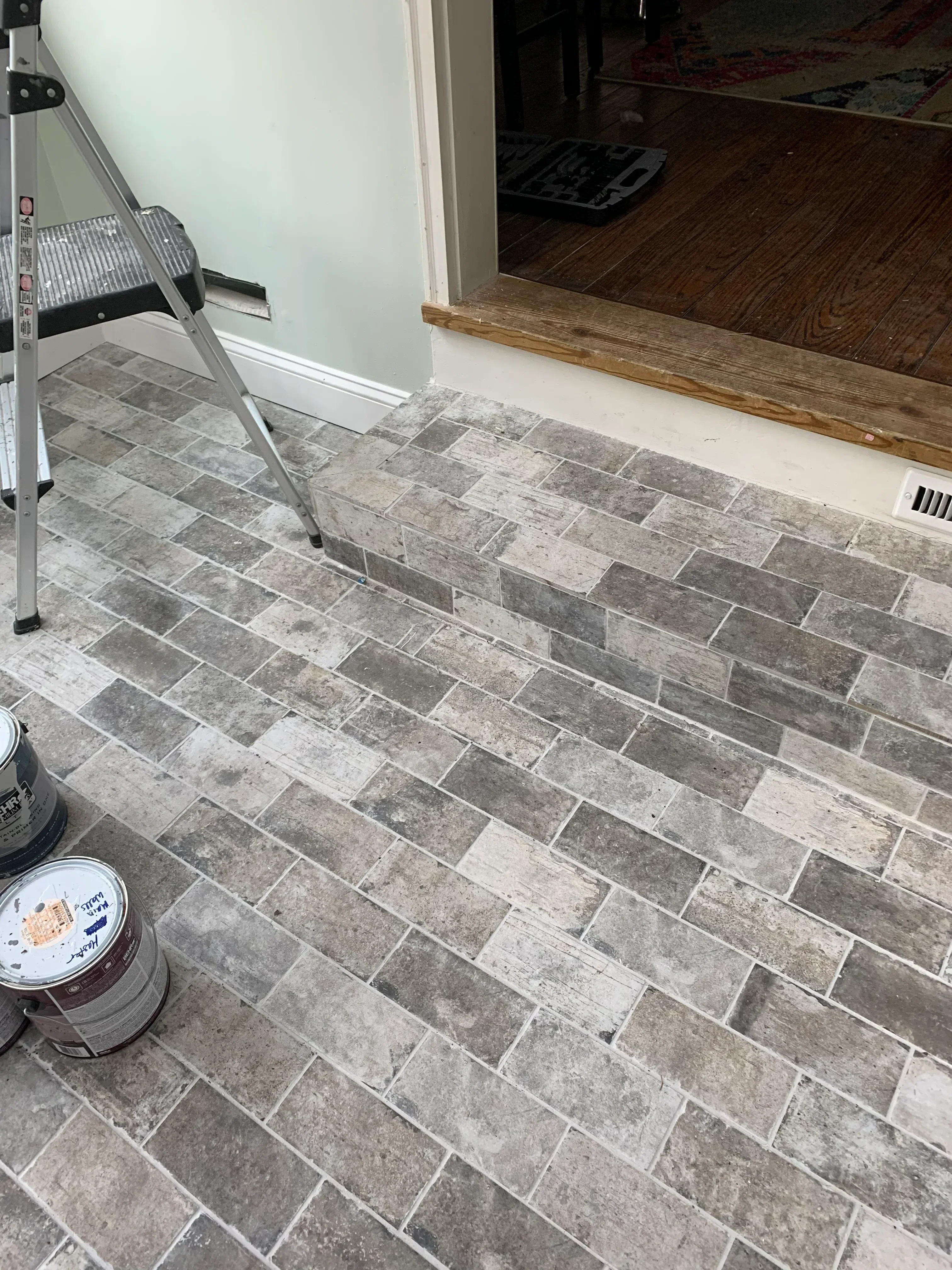Gray and white porcelain tile floor in herringbone pattern with white grout lines