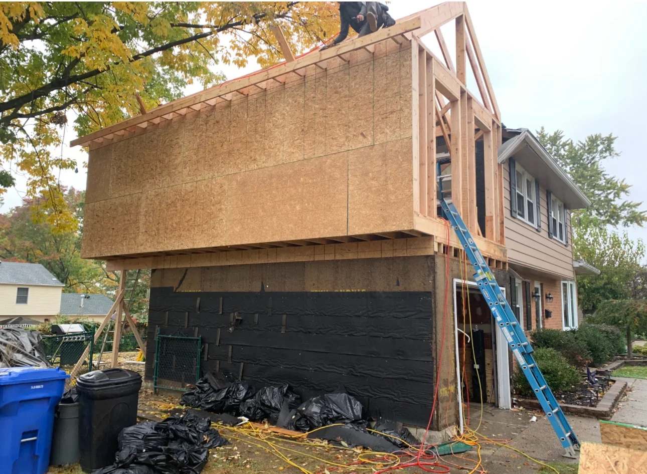 Second story wood framing addition above garage with OSB sheathing and roof trusses under construction
