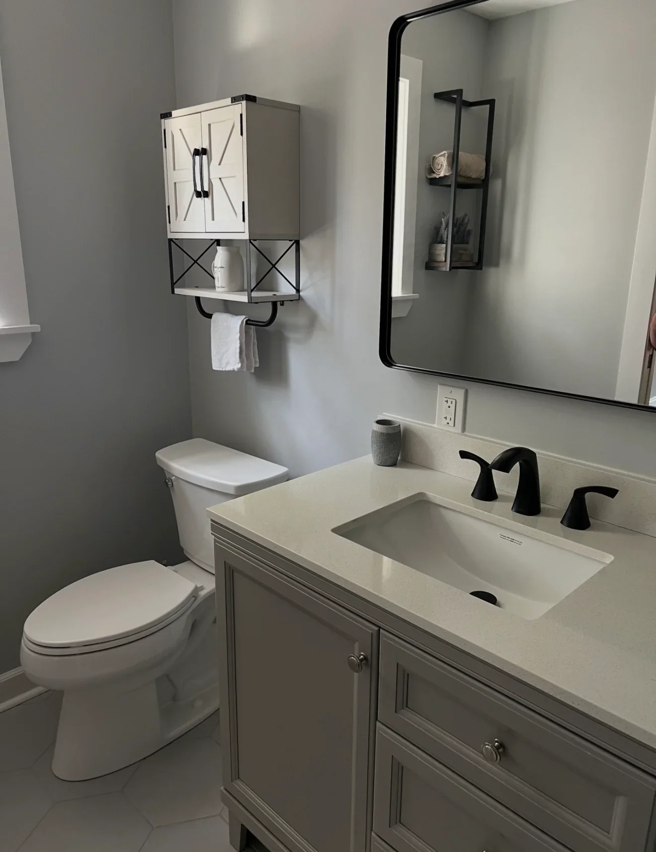 Bathroom vanity with white quartz countertop, black faucet, and wall-mounted storage cabinet