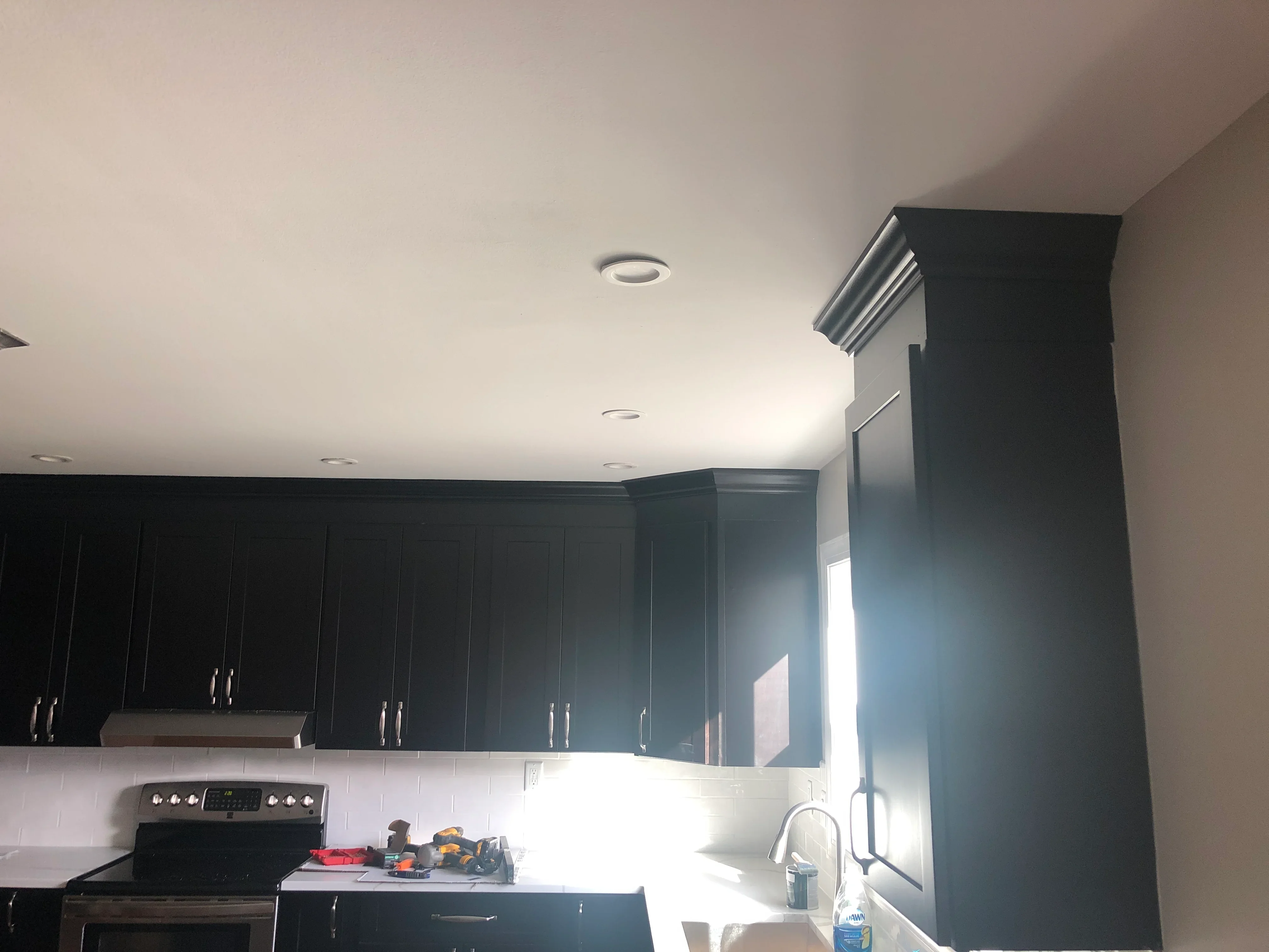 Black cabinetry, white subway tile backsplash, quartz counters, recessed lighting in modern kitchen