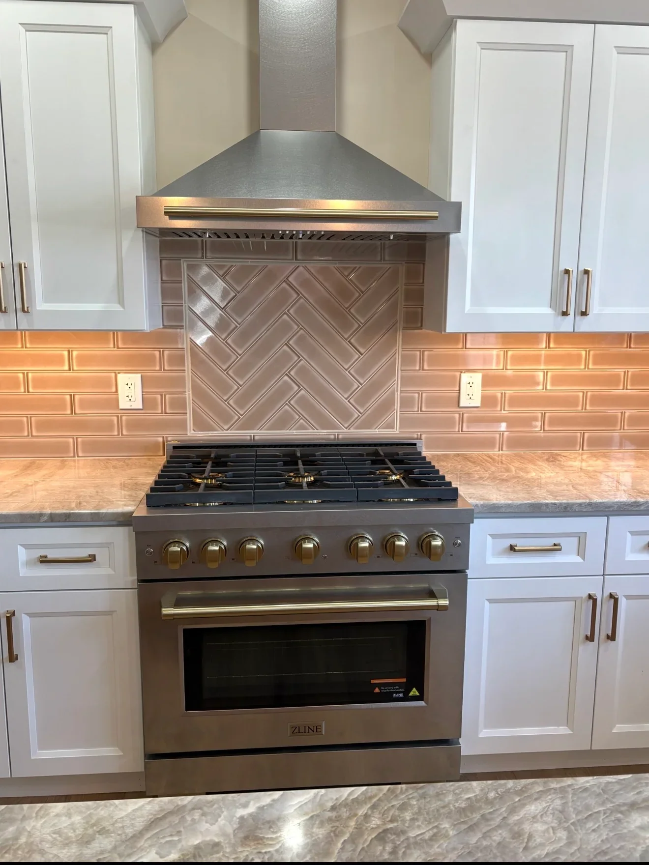 Professional stainless steel range with herringbone tile backsplash and white cabinetry in modern kitchen