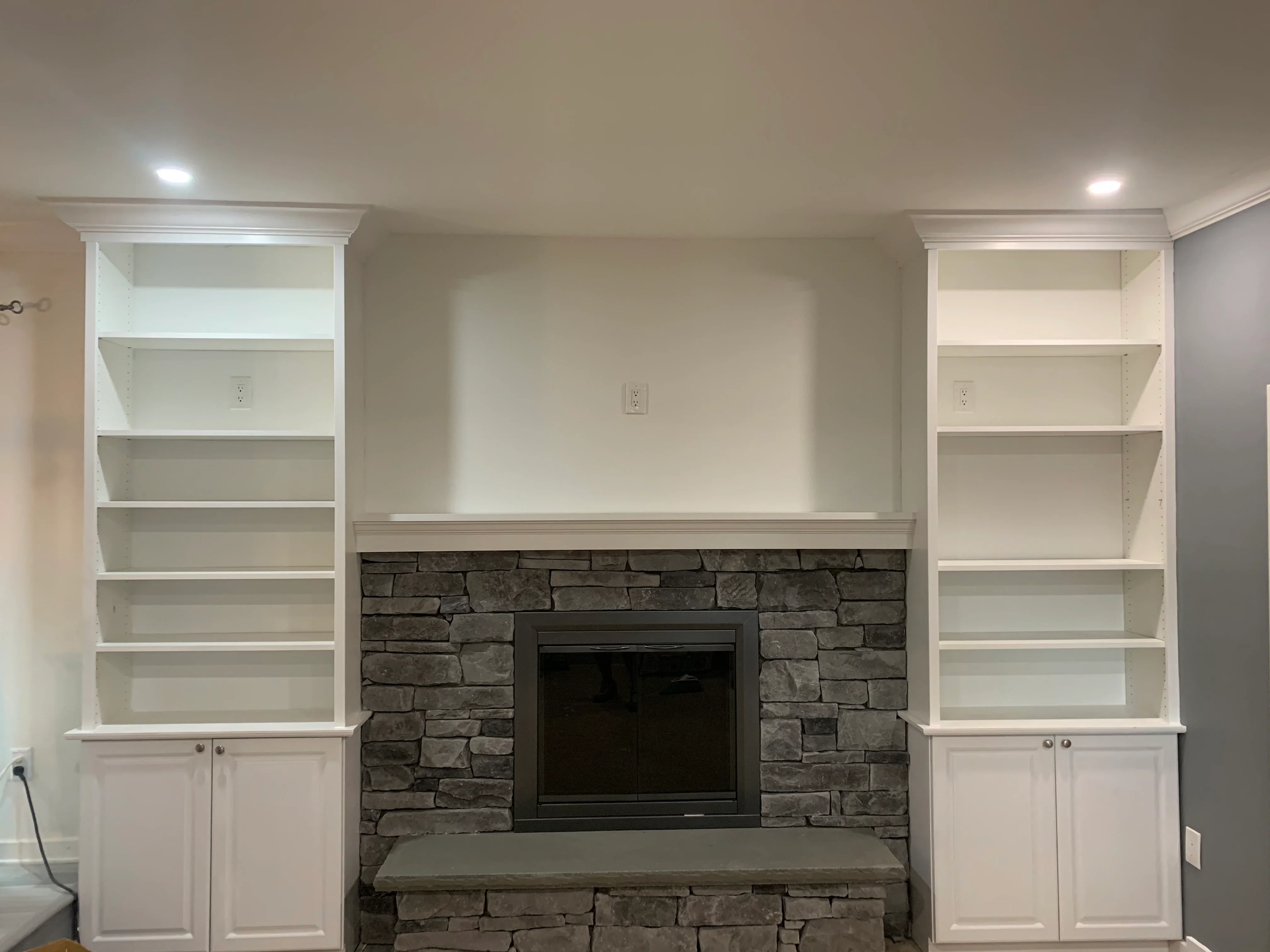 White built-in shelving with stacked stone fireplace surround and black insert