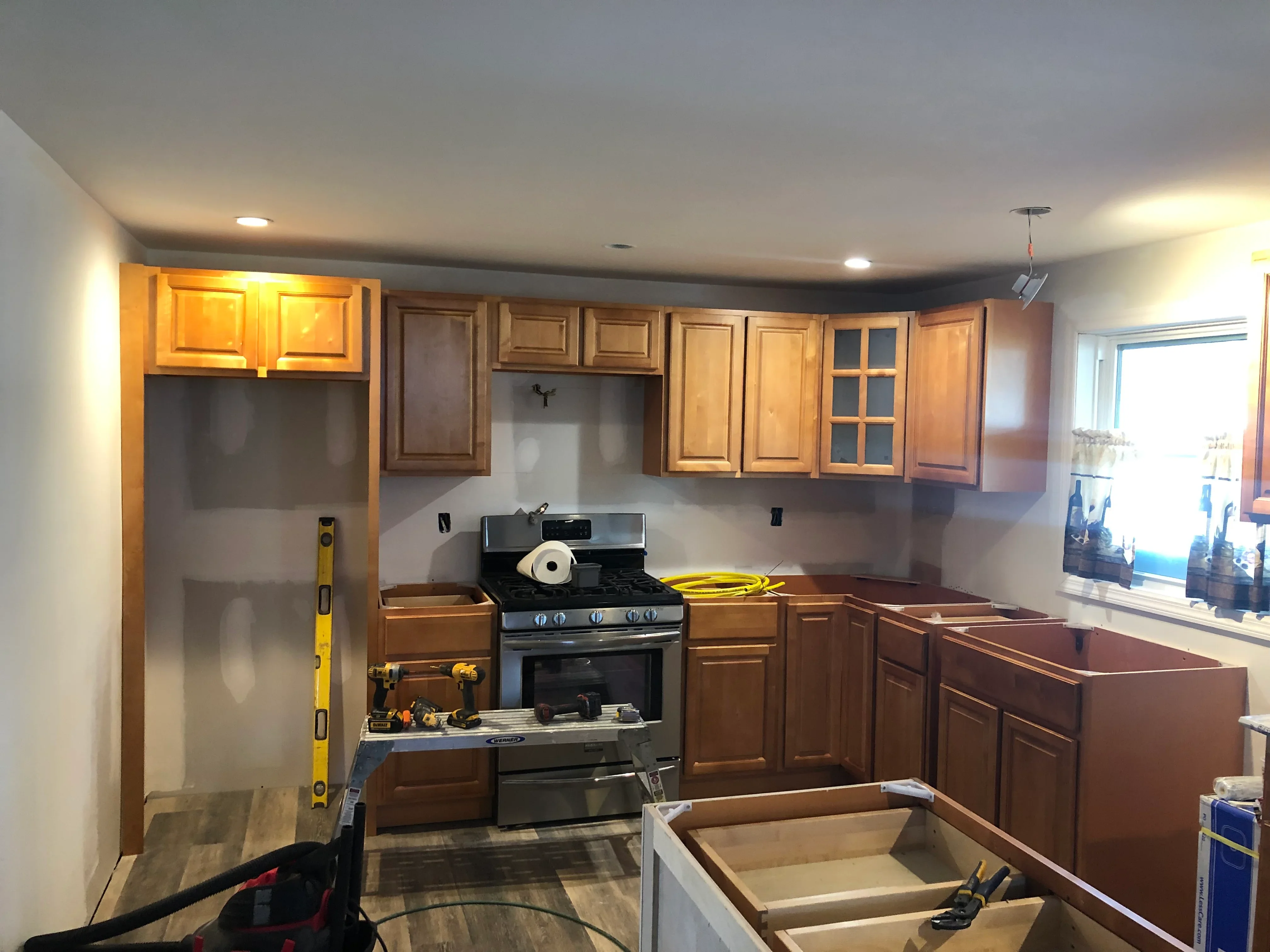 Kitchen remodel with wood cabinetry, black gas range, recessed lighting, and in-progress installation