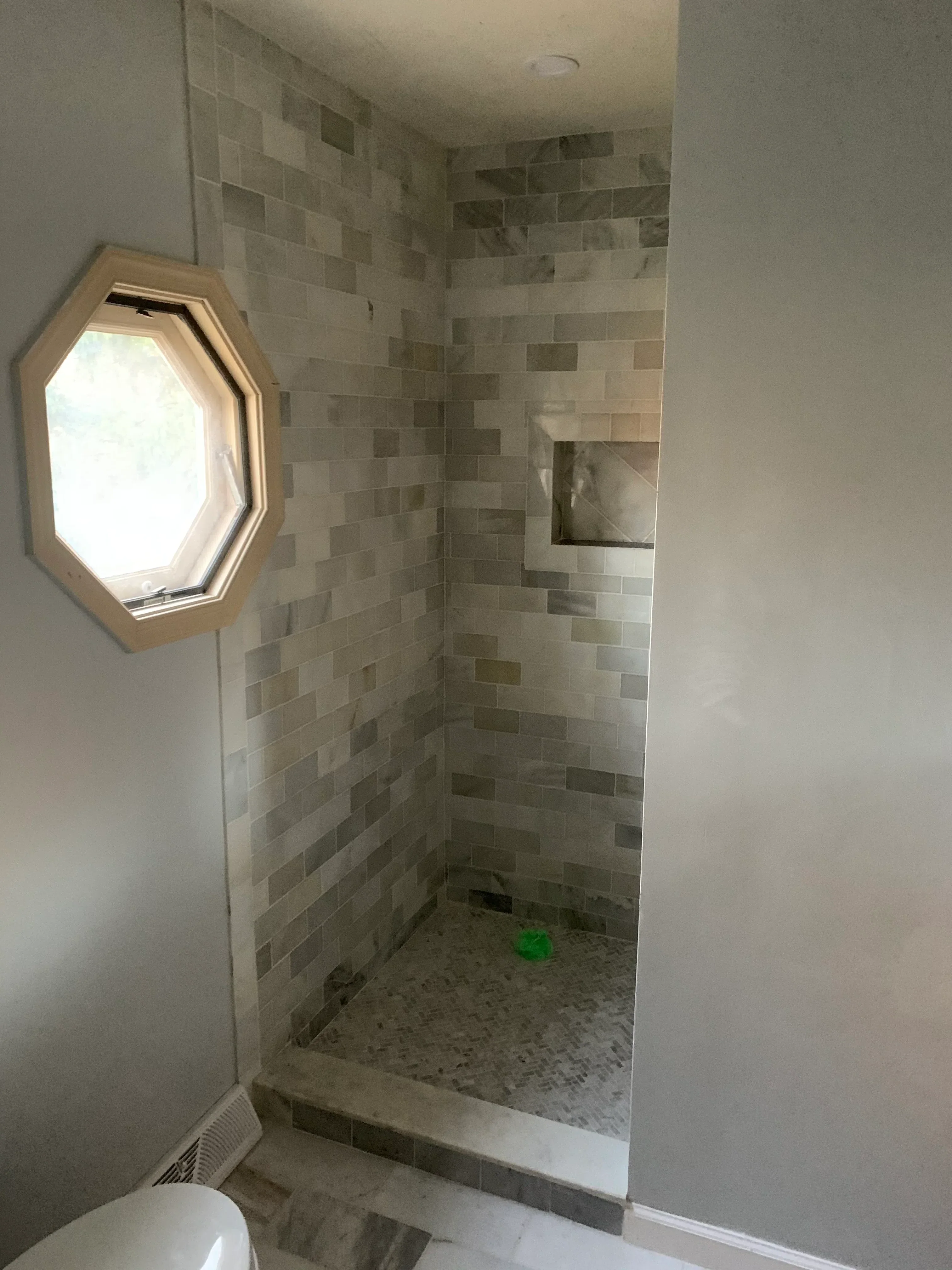 Walk-in shower with stacked bond ceramic tile walls and floor, recessed niche, and linear drain