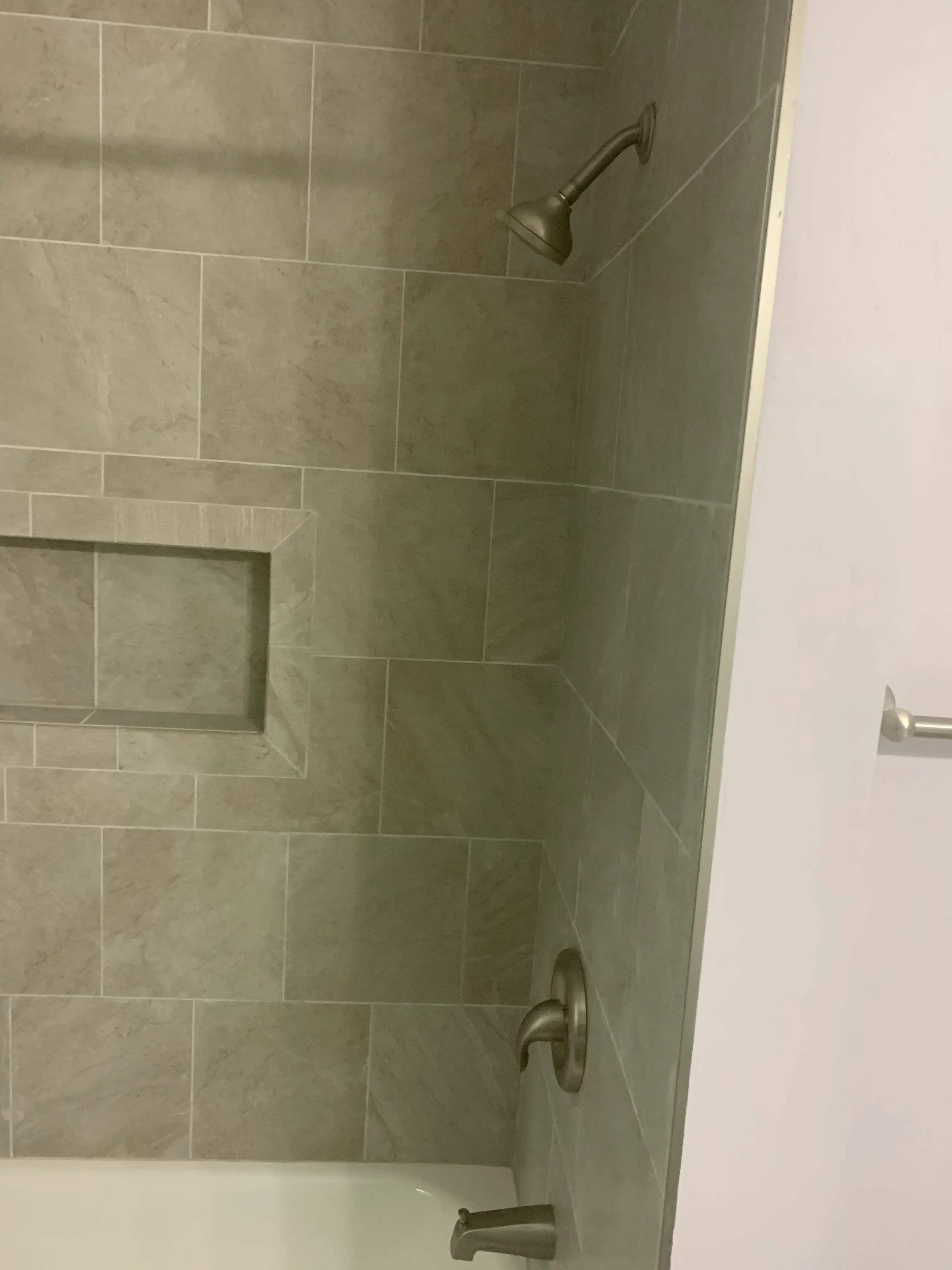 Gray tile shower with running bond pattern, niche, and brushed nickel fixtures