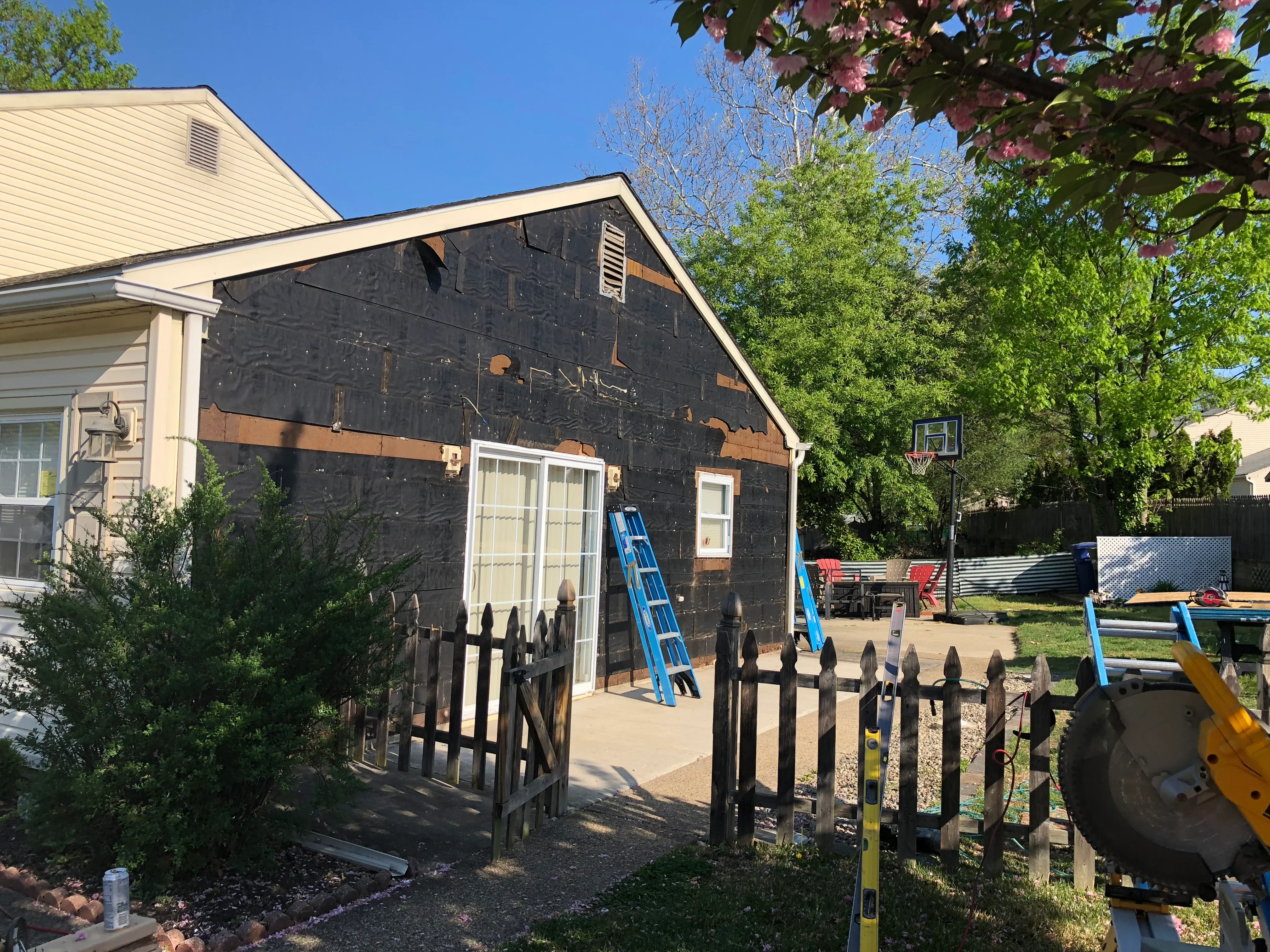 New home addition with black sheathing, white double doors, and gable roof framing in progress