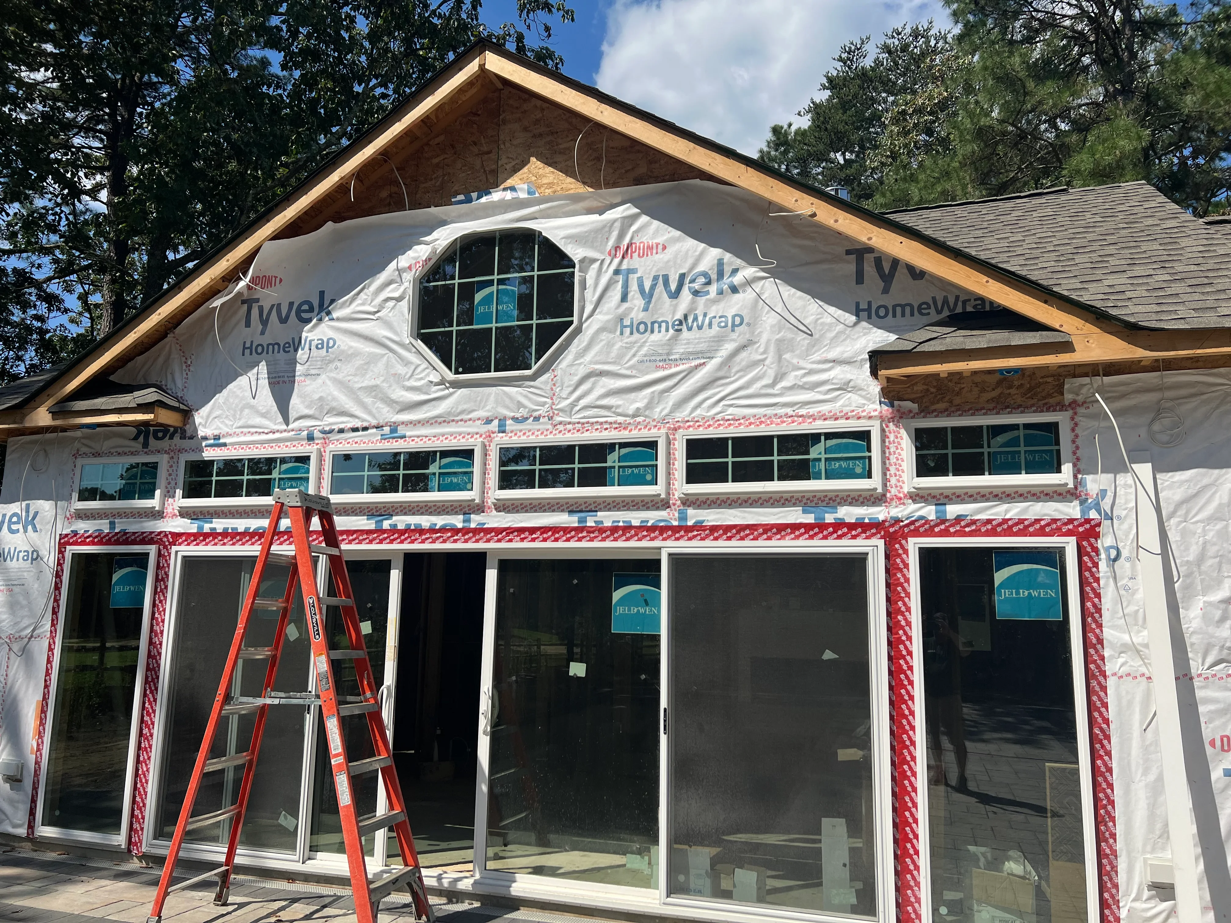 Home exterior under renovation with new windows, Tyvek wrap, and red housewrap tape
