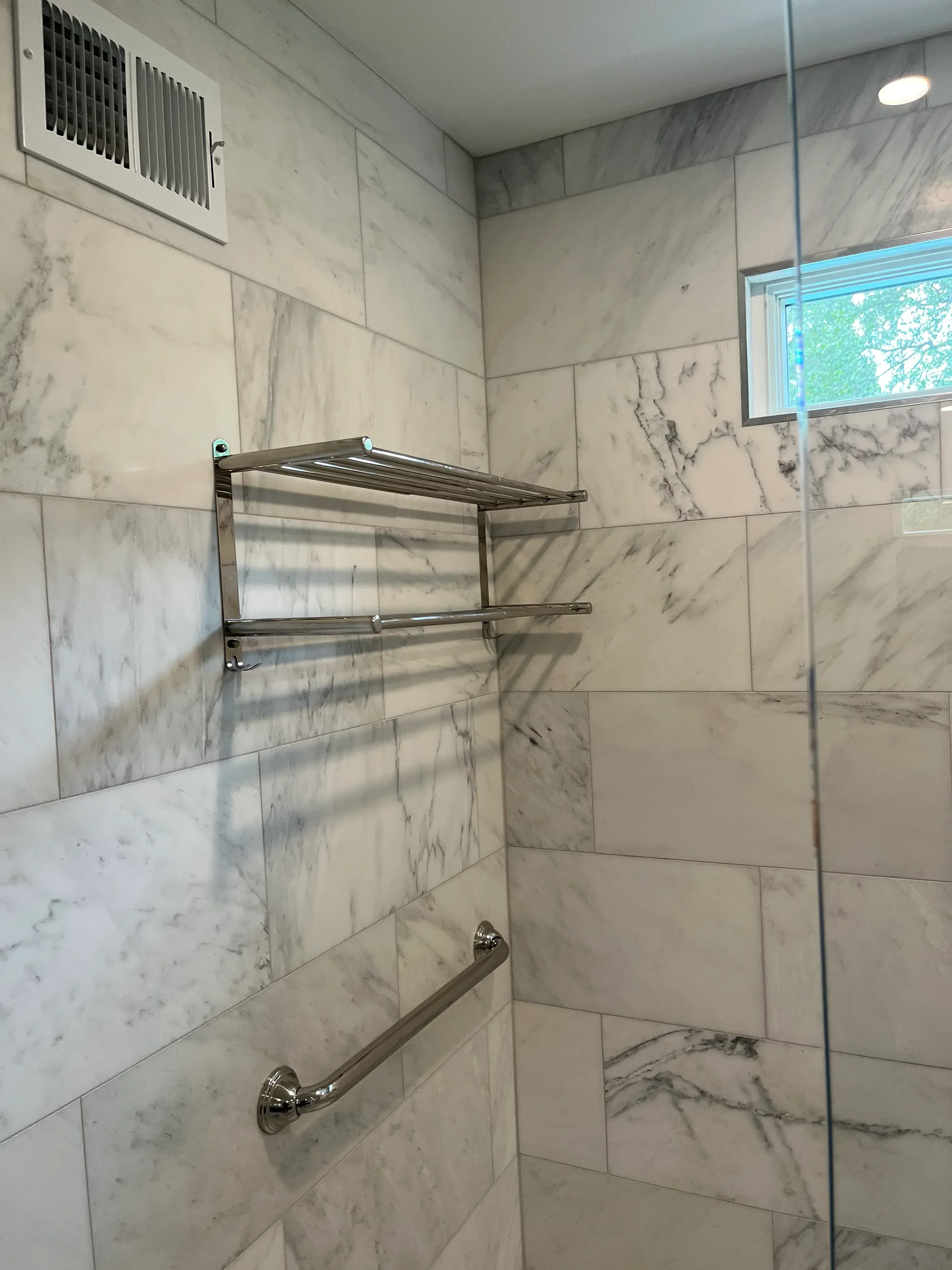 Marble tile bathroom with frameless glass shower enclosure and chrome fixtures