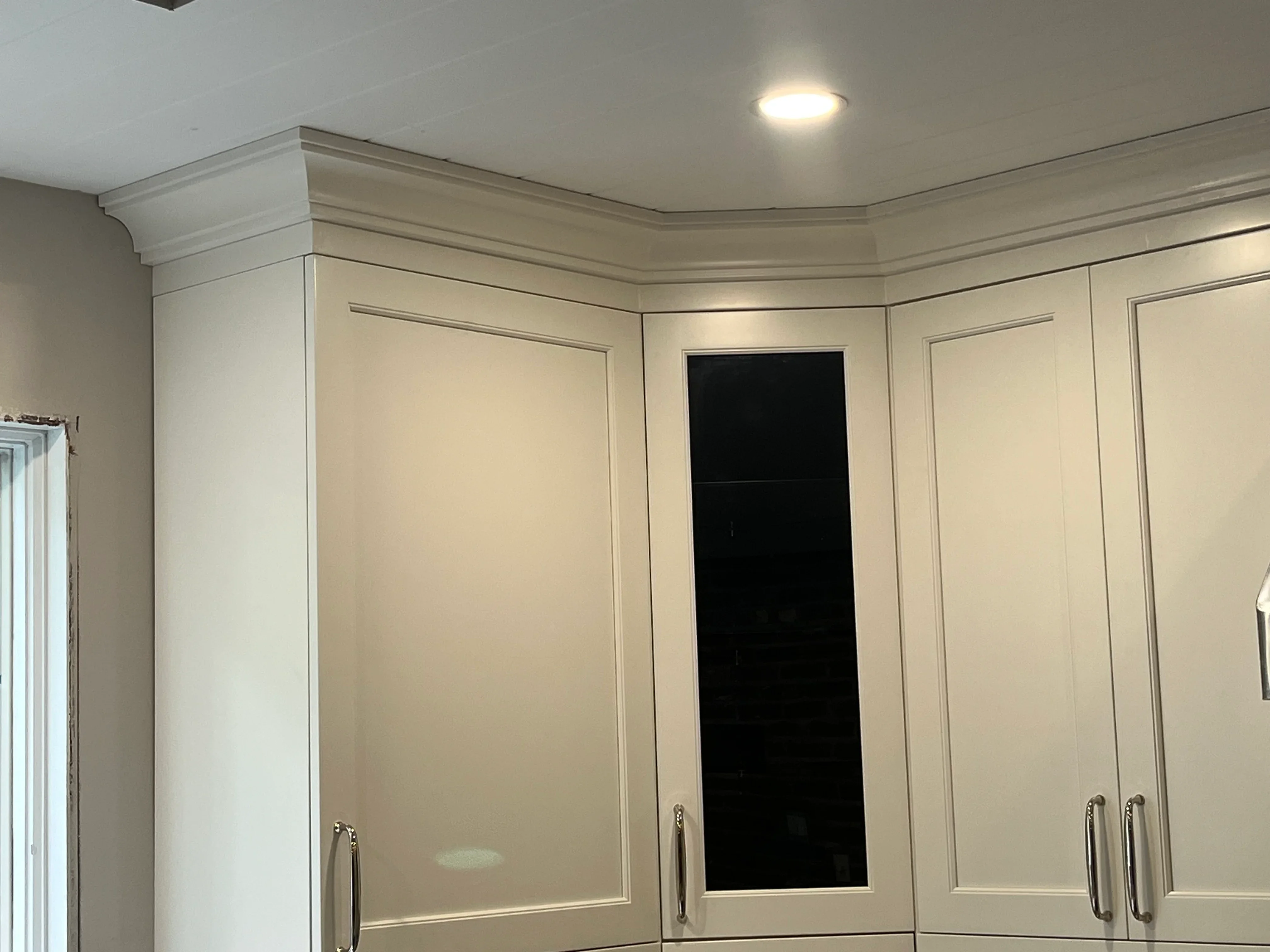 Cream kitchen cabinets with recessed panels, chrome handles, and crown molding detail