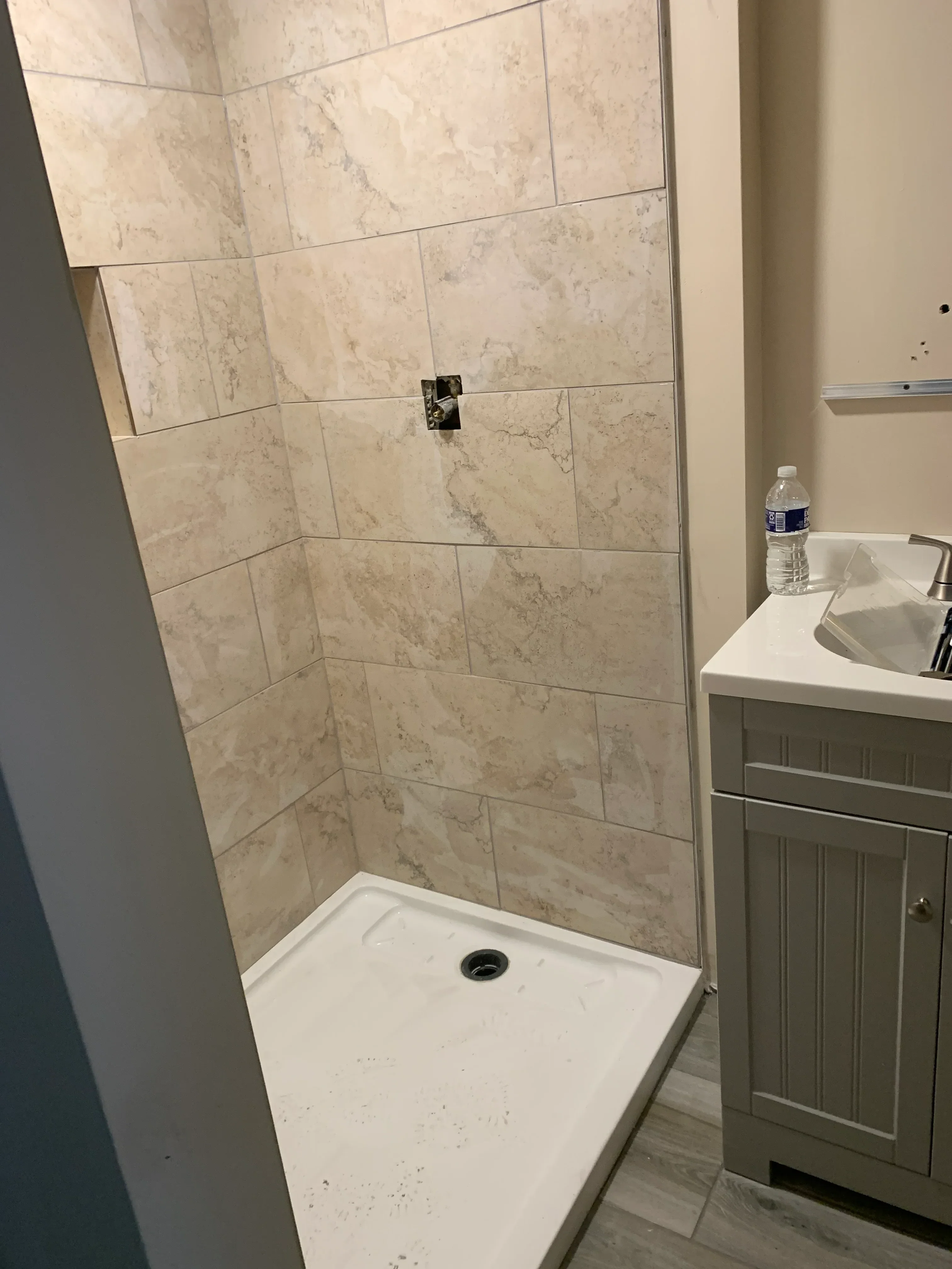 Large-format marble-look porcelain tile shower walls with white pan and recessed niche
