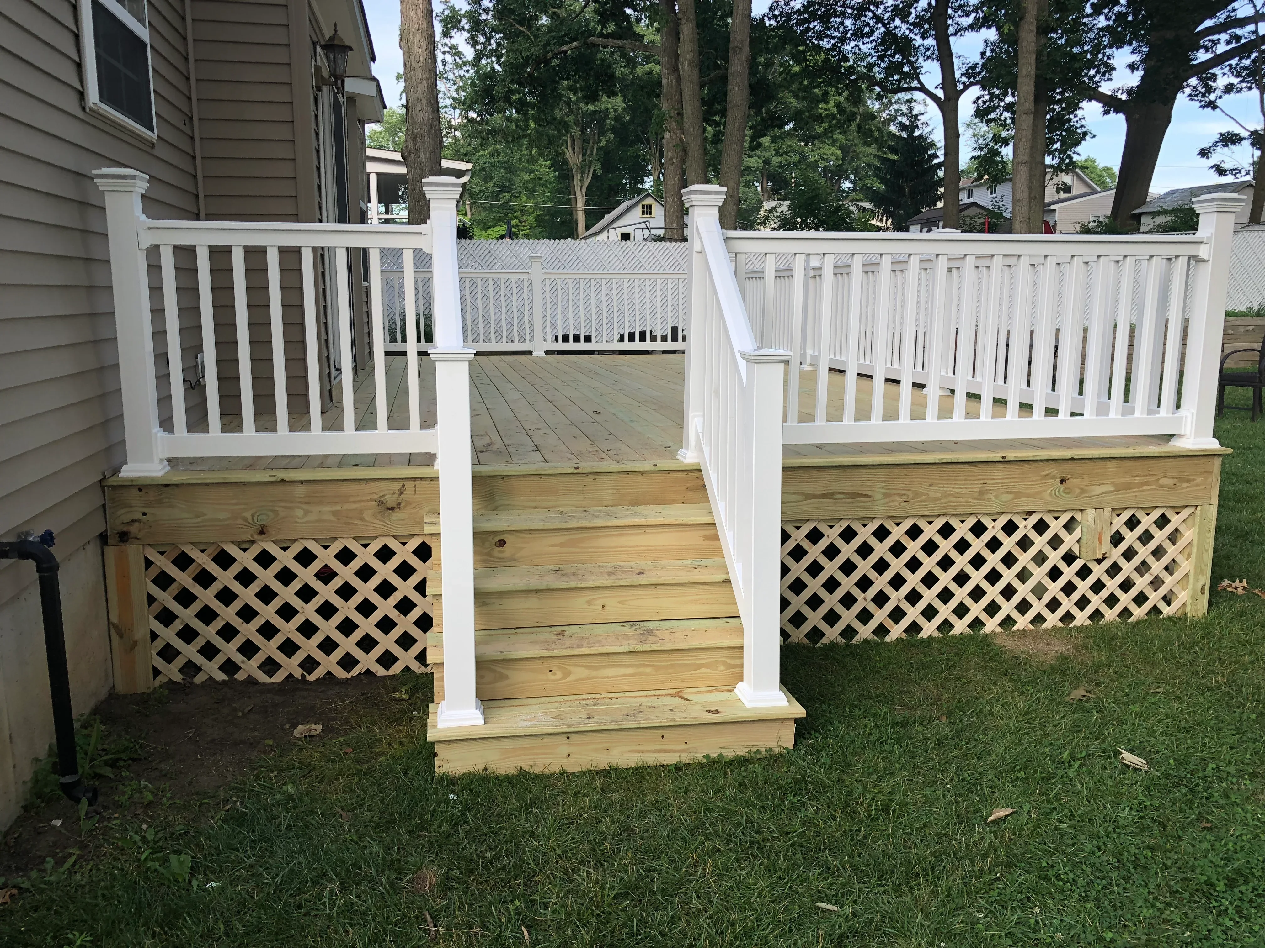 Composite deck with white vinyl railings, balusters, and lattice skirting panels