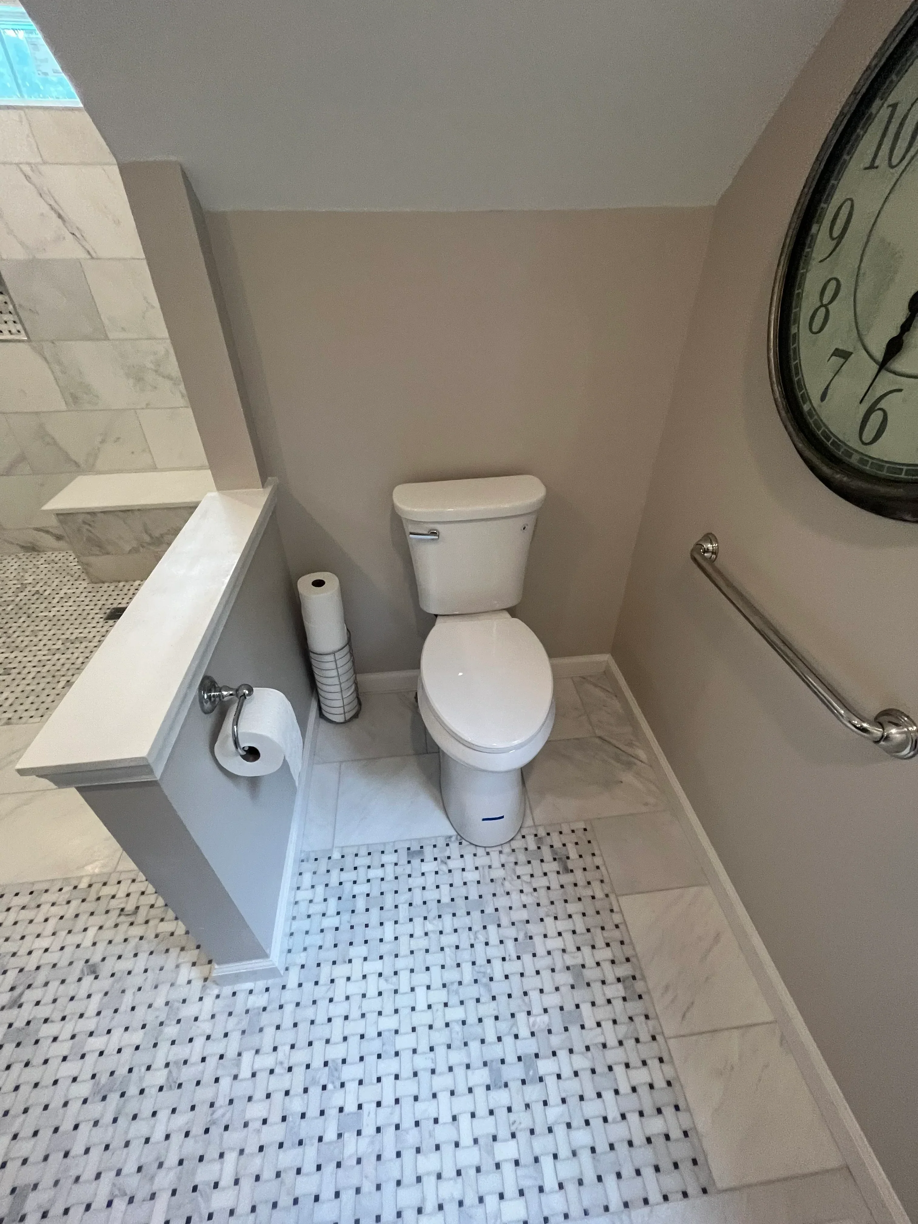 Bathroom with marble tile wainscot, white pedestal sink, pegboard storage wall, and chrome fixtures