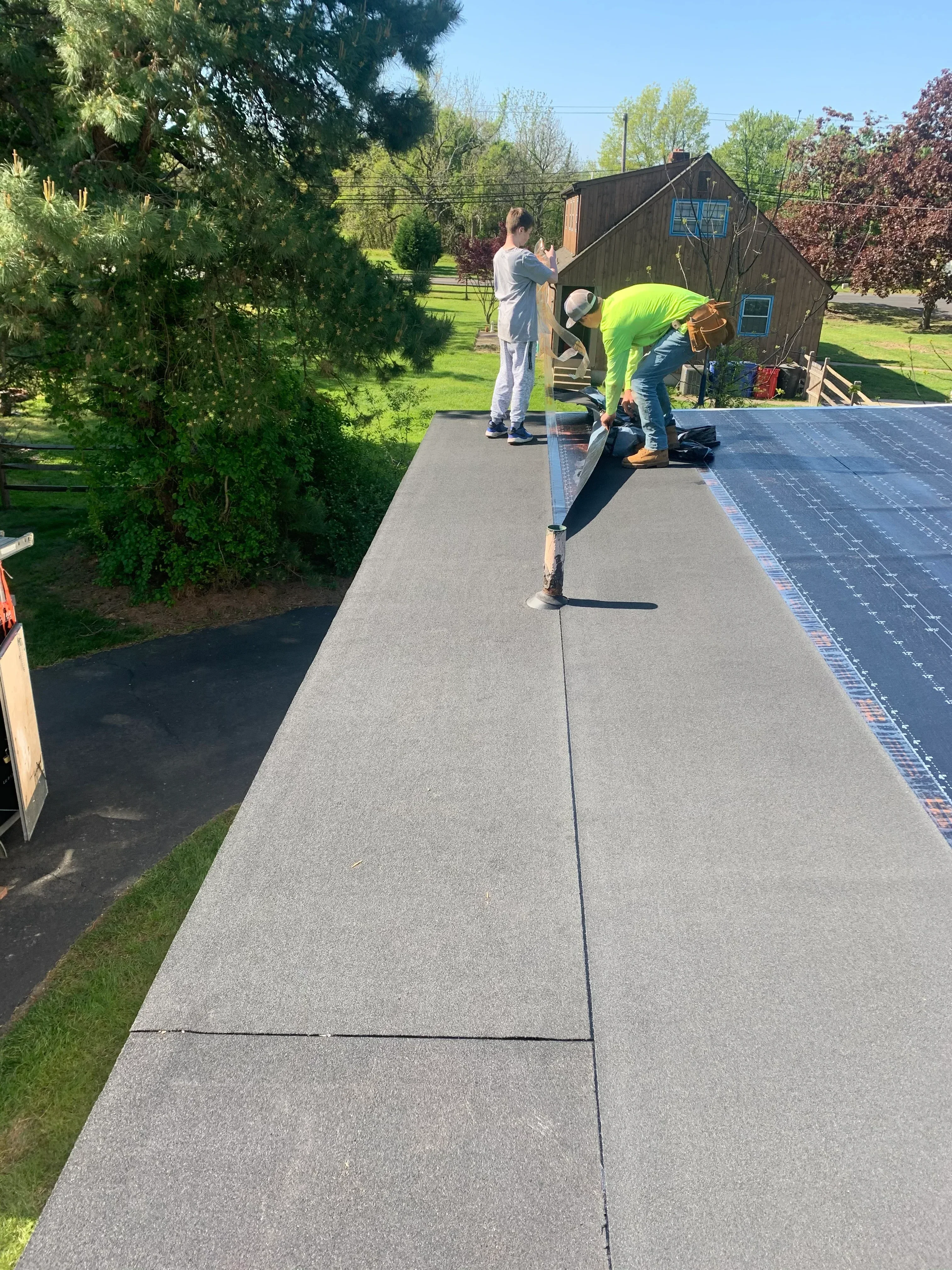 Worker installing gray fiber cement siding panels on residential home exterior