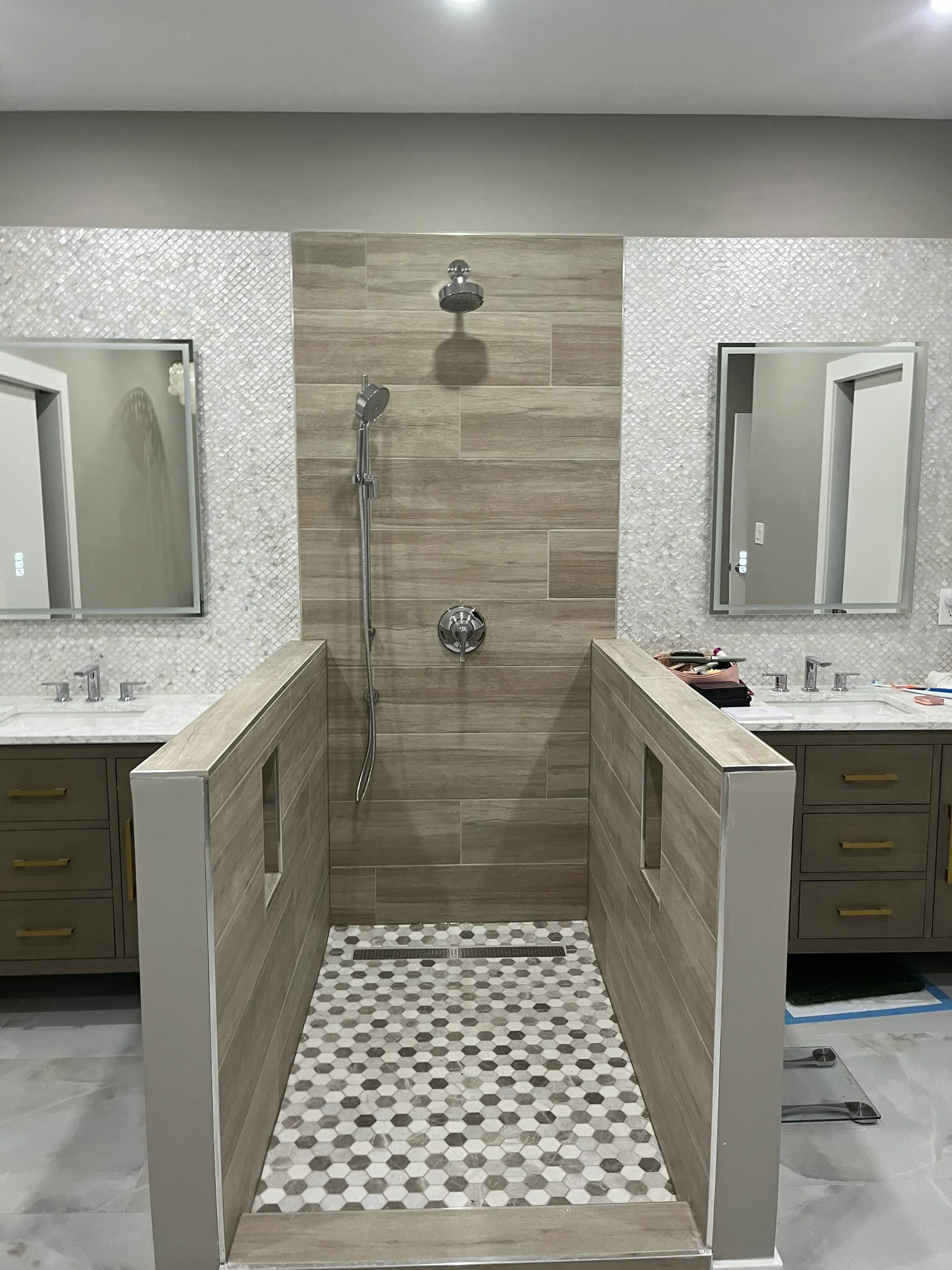 Bathroom with wood-look tile floor, geometric mosaic wall tile, walk-in shower with glass enclosure, and floating vanity