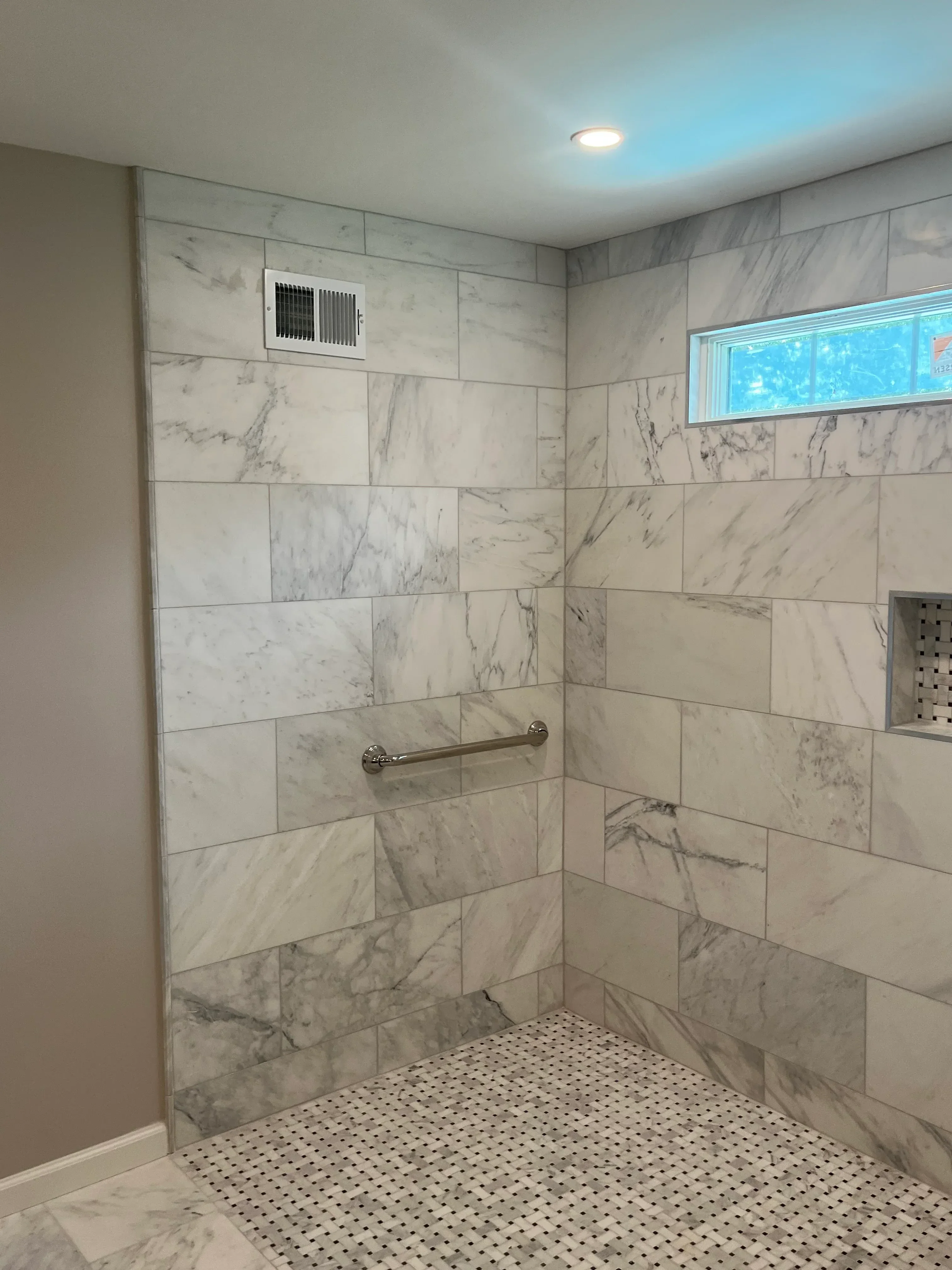 Marble-look porcelain tile bathroom with mosaic accent wall and recessed lighting