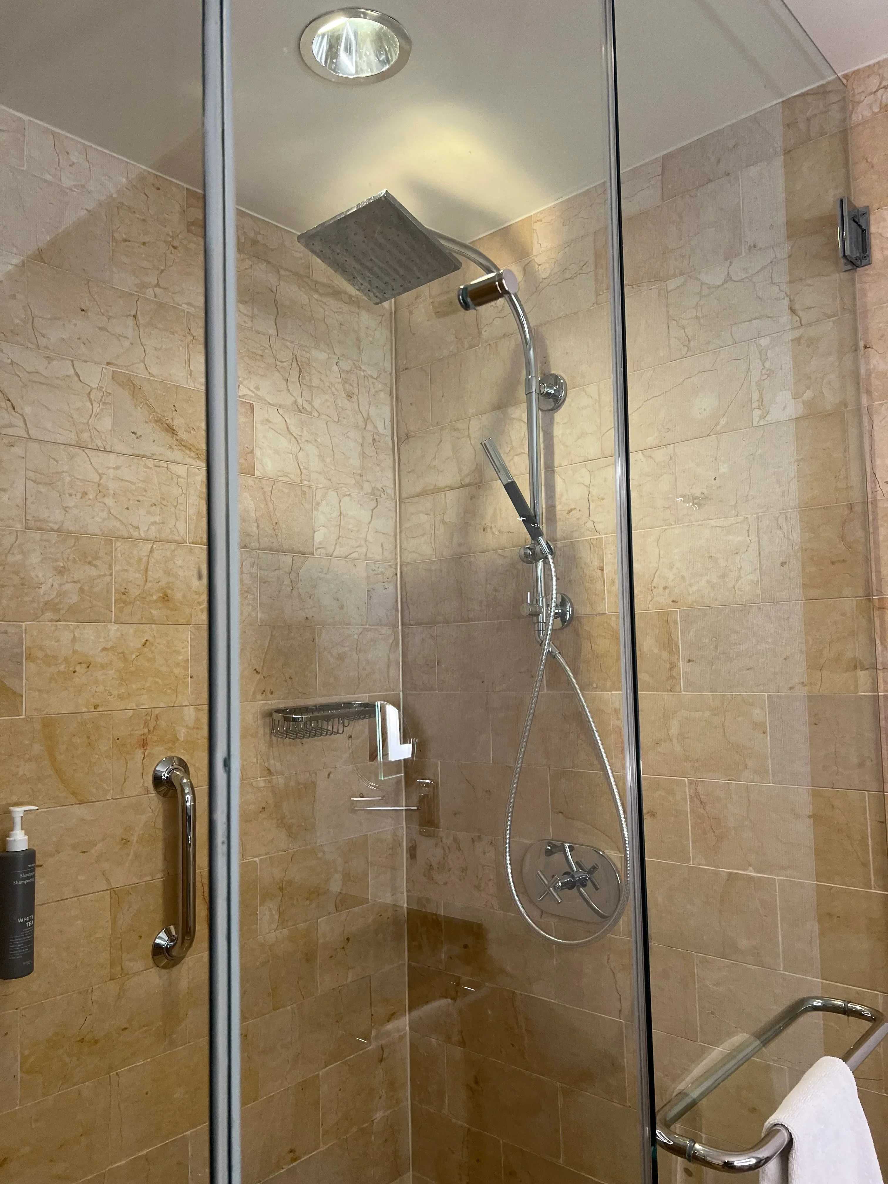 Marble tile shower with frameless glass door and chrome fixtures