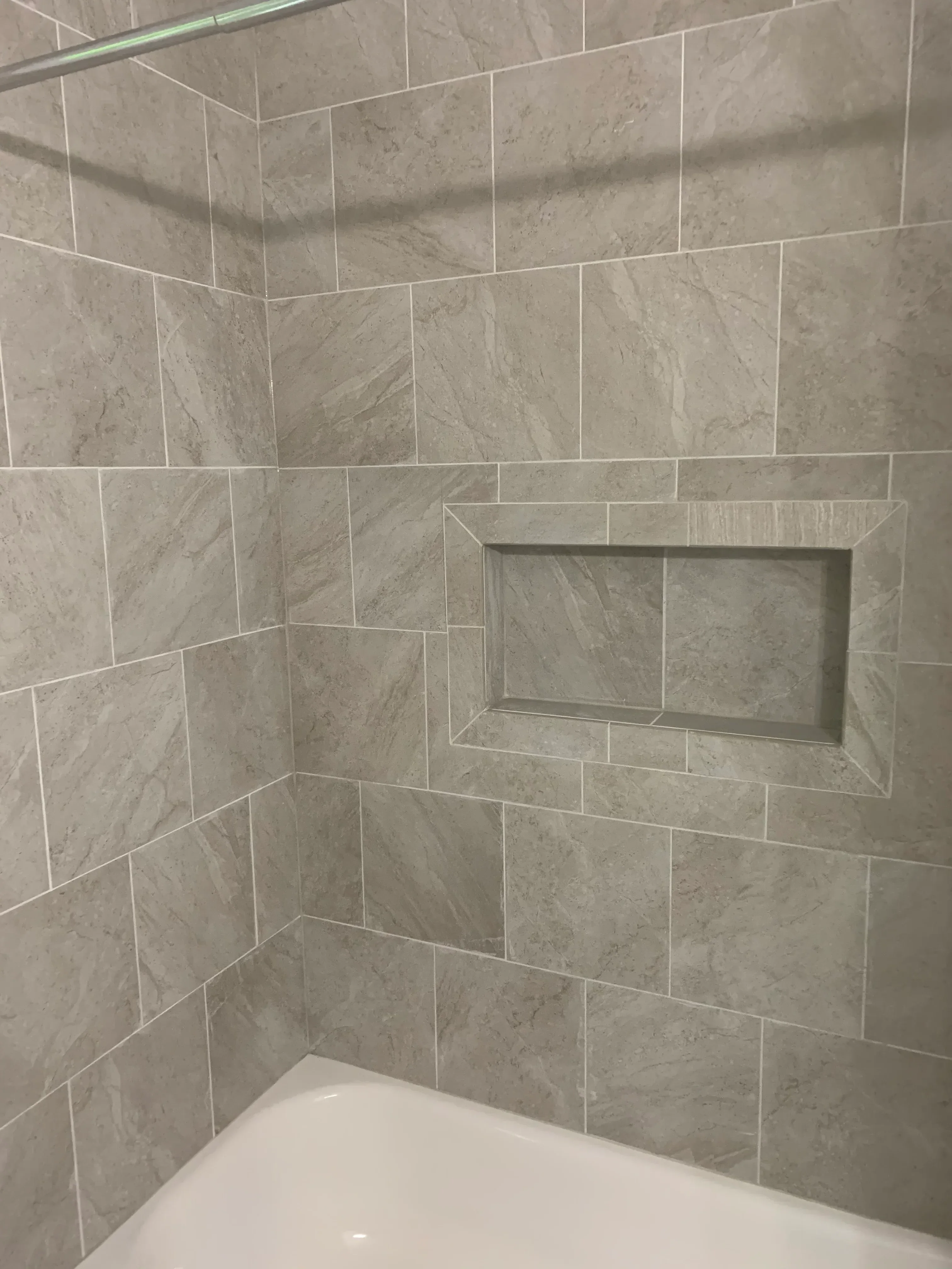 Gray marble tile shower with staggered brick pattern and built-in recessed niche