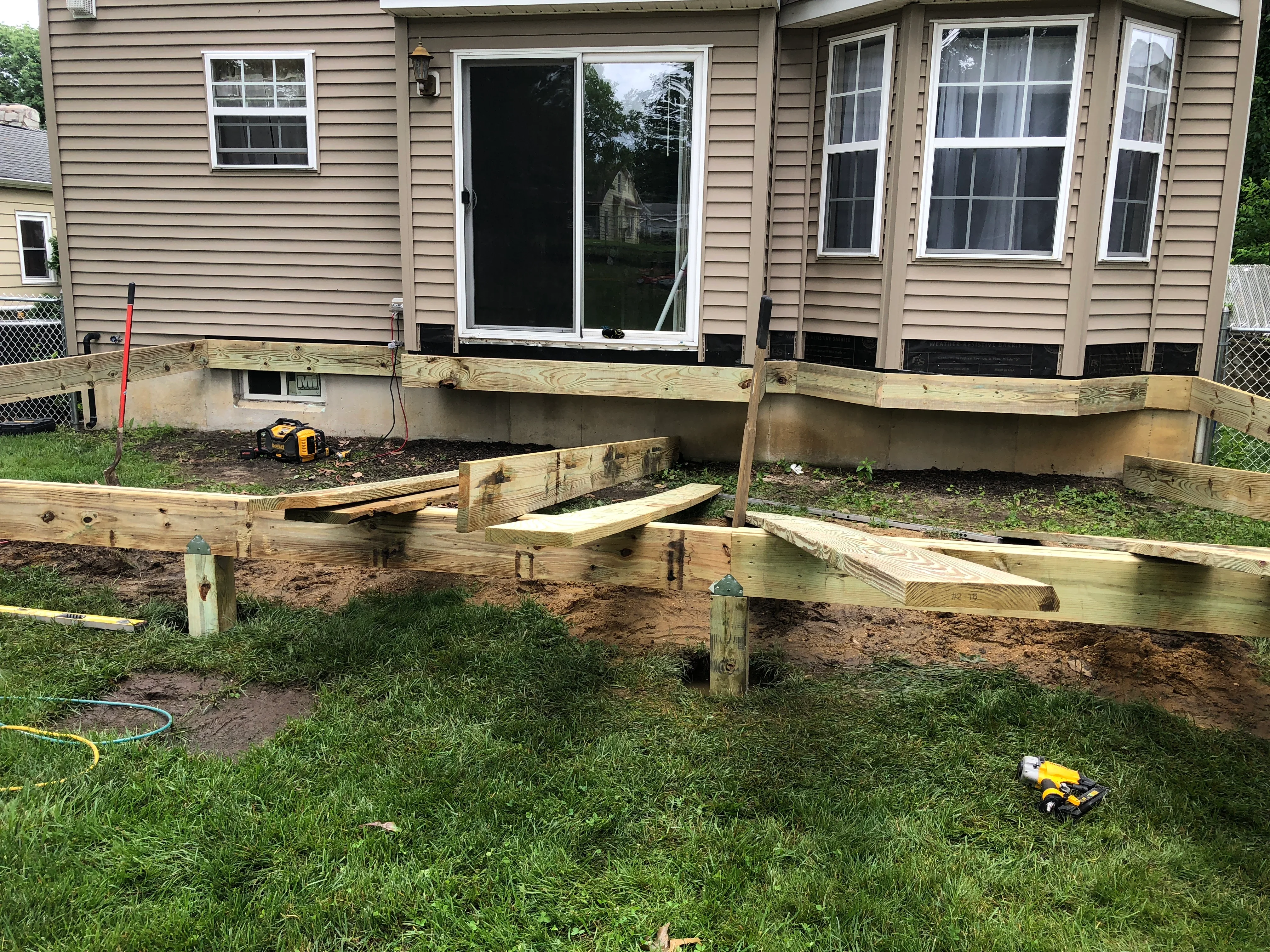 Pressure-treated wood deck framing with concrete footings and support posts during construction