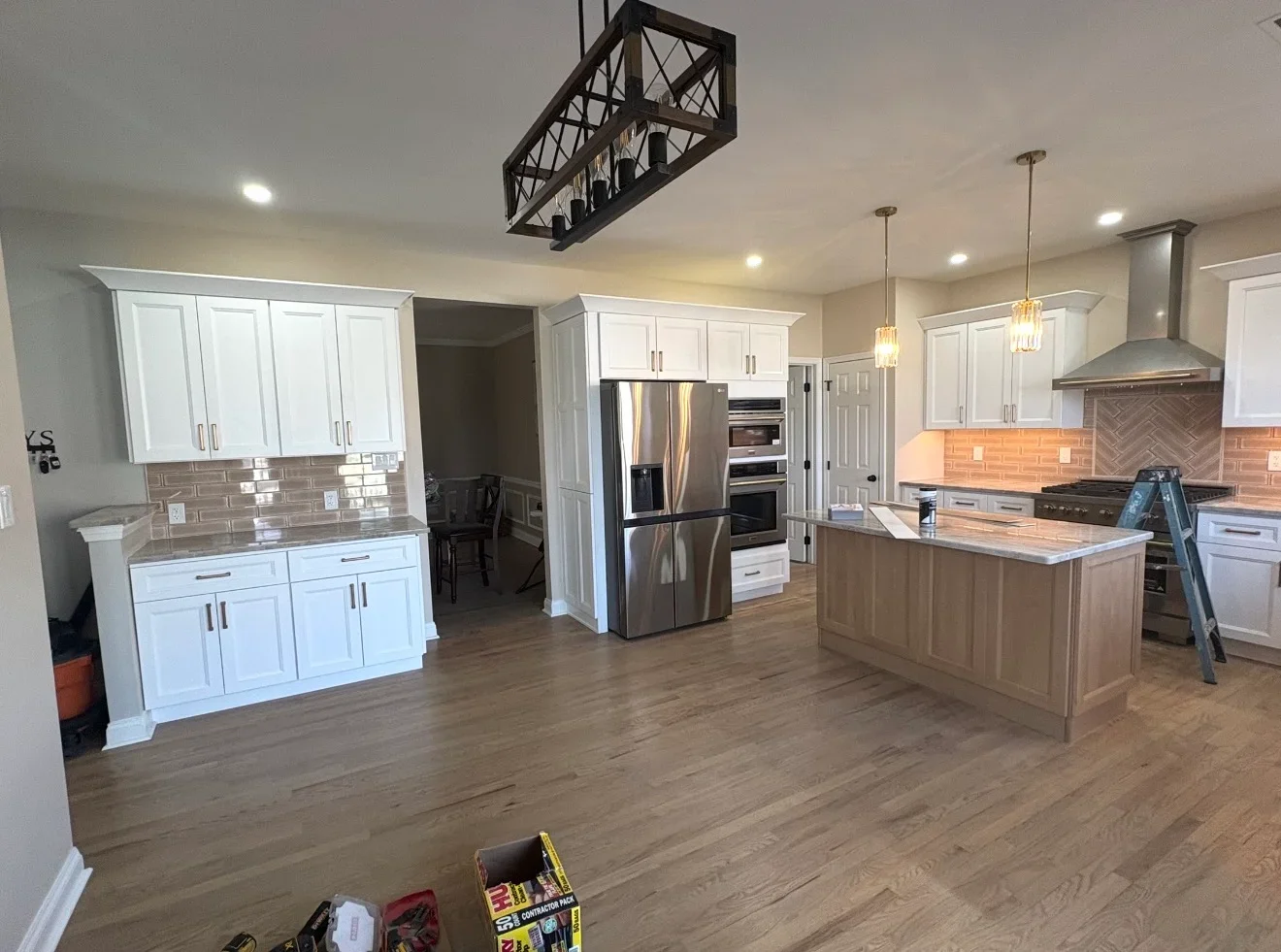 Modern kitchen with white cabinets, stainless steel appliances, brick backsplash, and wood island