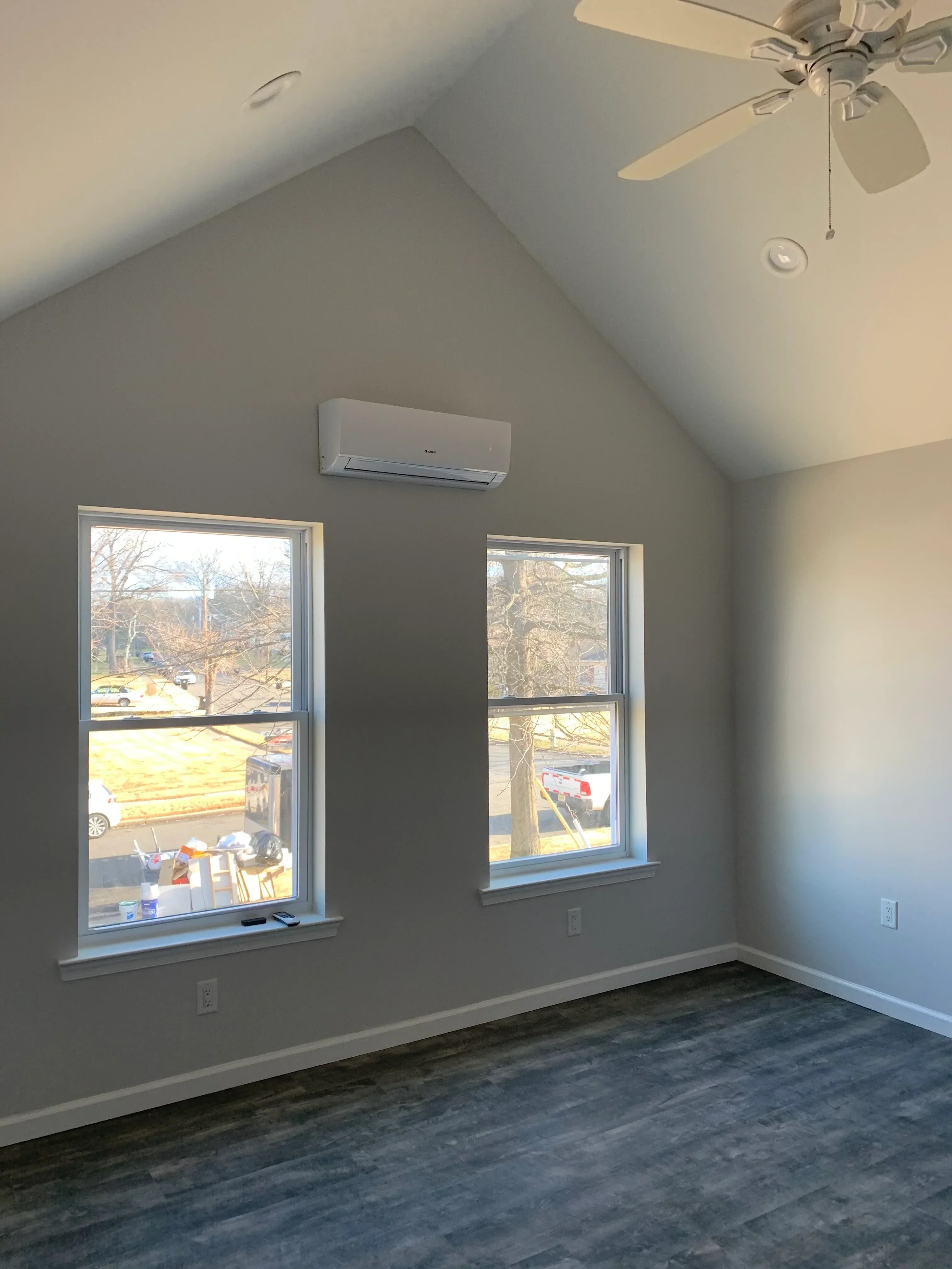 Attic bedroom with two new aluminum-framed windows, drywall, and ceiling fan installation