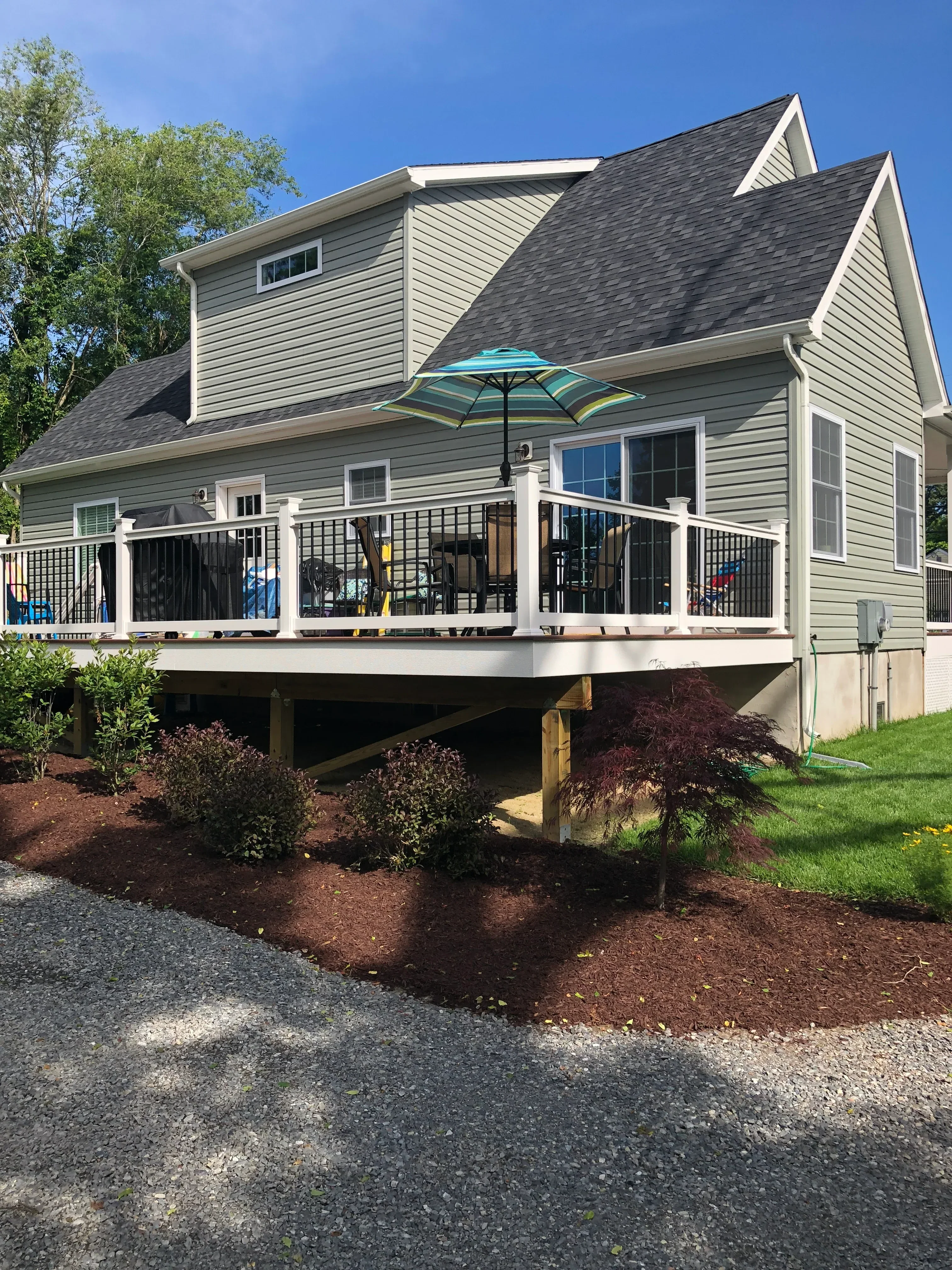 Modern home with metal siding, pitched metal roof, and multi-level deck with black railings