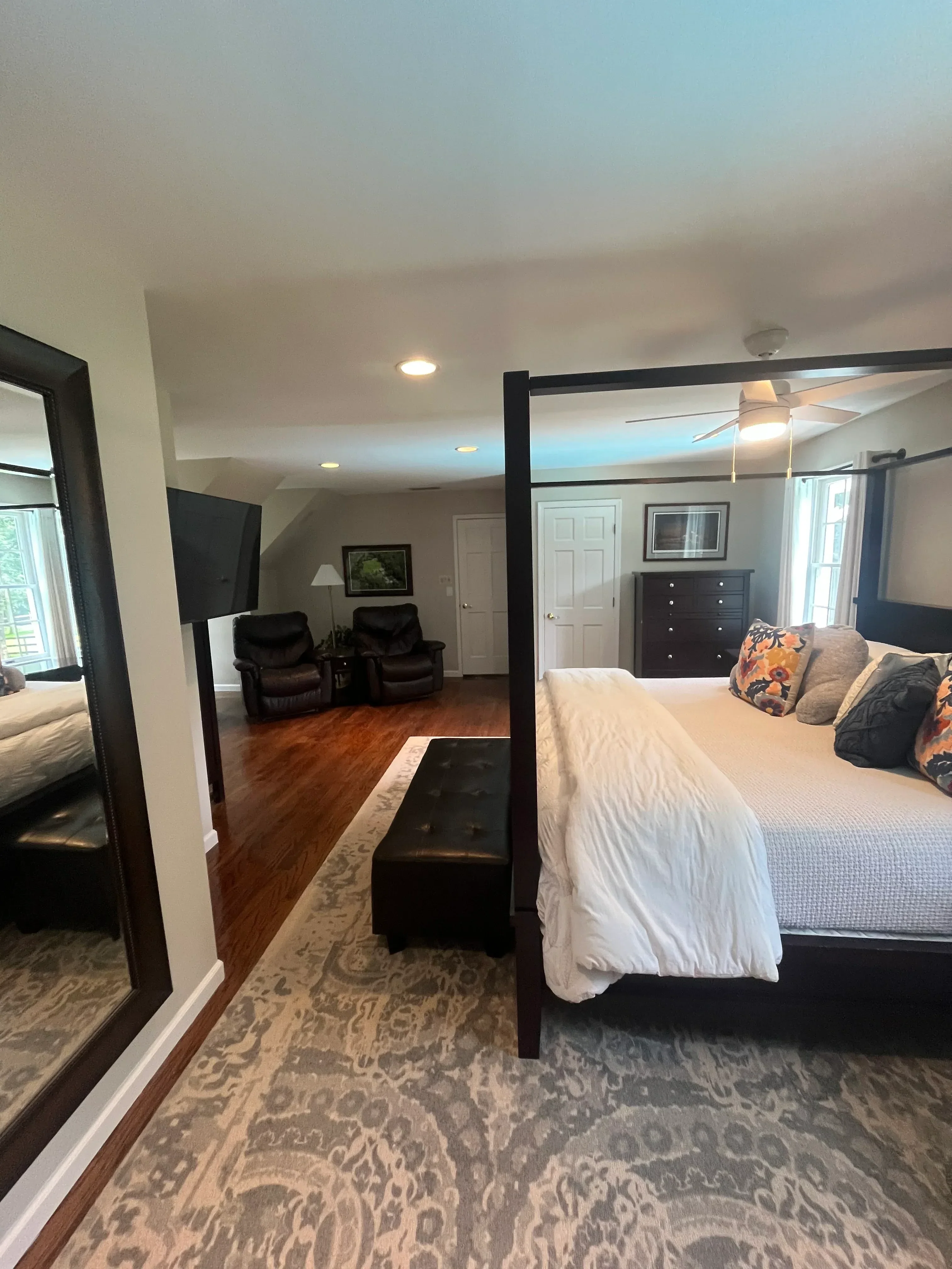Master bedroom with hardwood floors, patterned wallpaper, black bed frame, and custom cabinetry