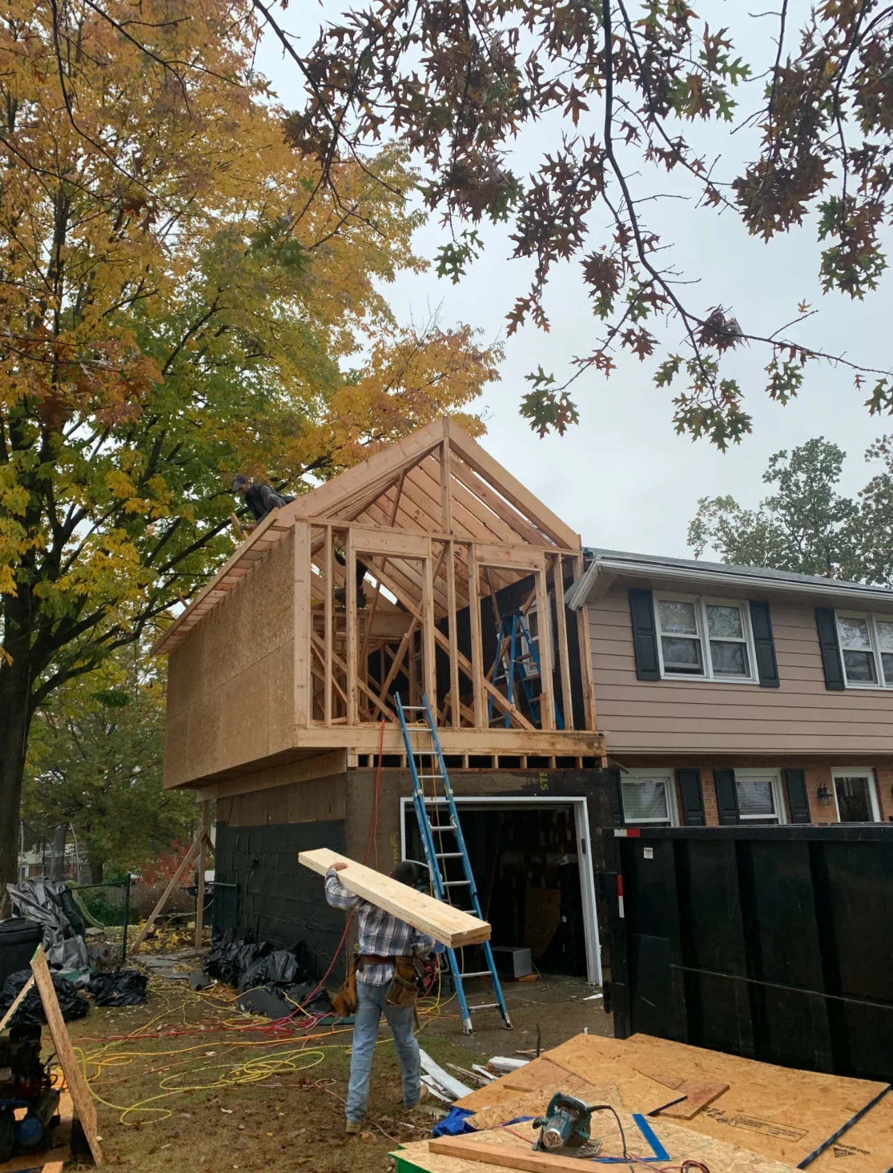 Second story wood framing addition with gable roof, wall studs, and window openings under construction