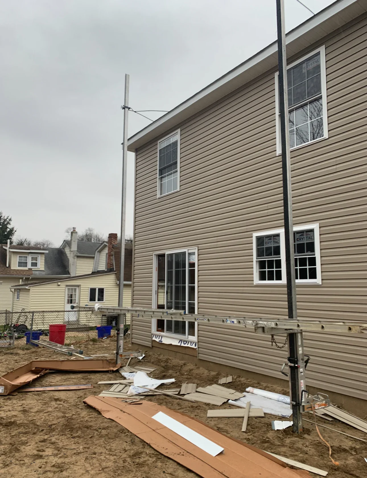 Two-story vinyl siding addition with double-hung windows and white trim during construction
