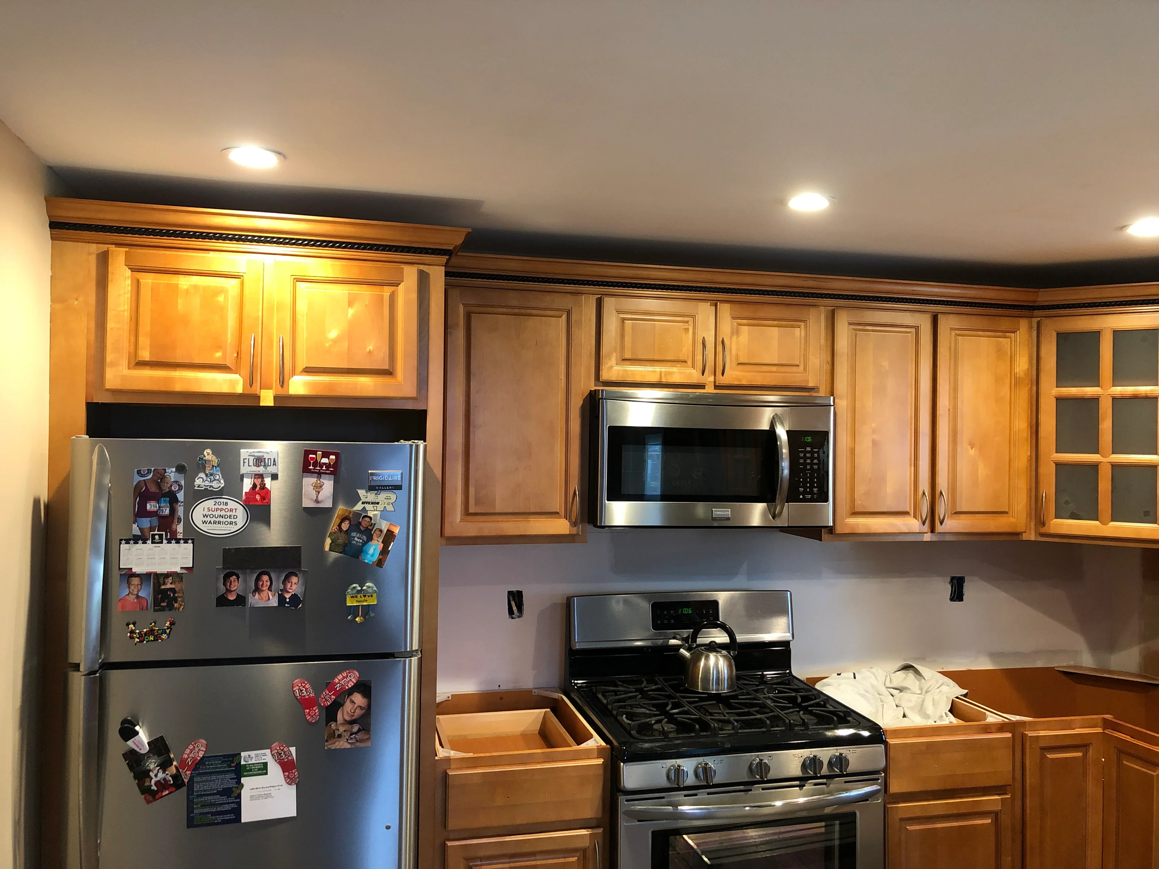 Kitchen with honey-toned wood cabinetry, stainless steel gas range and microwave, recessed lighting