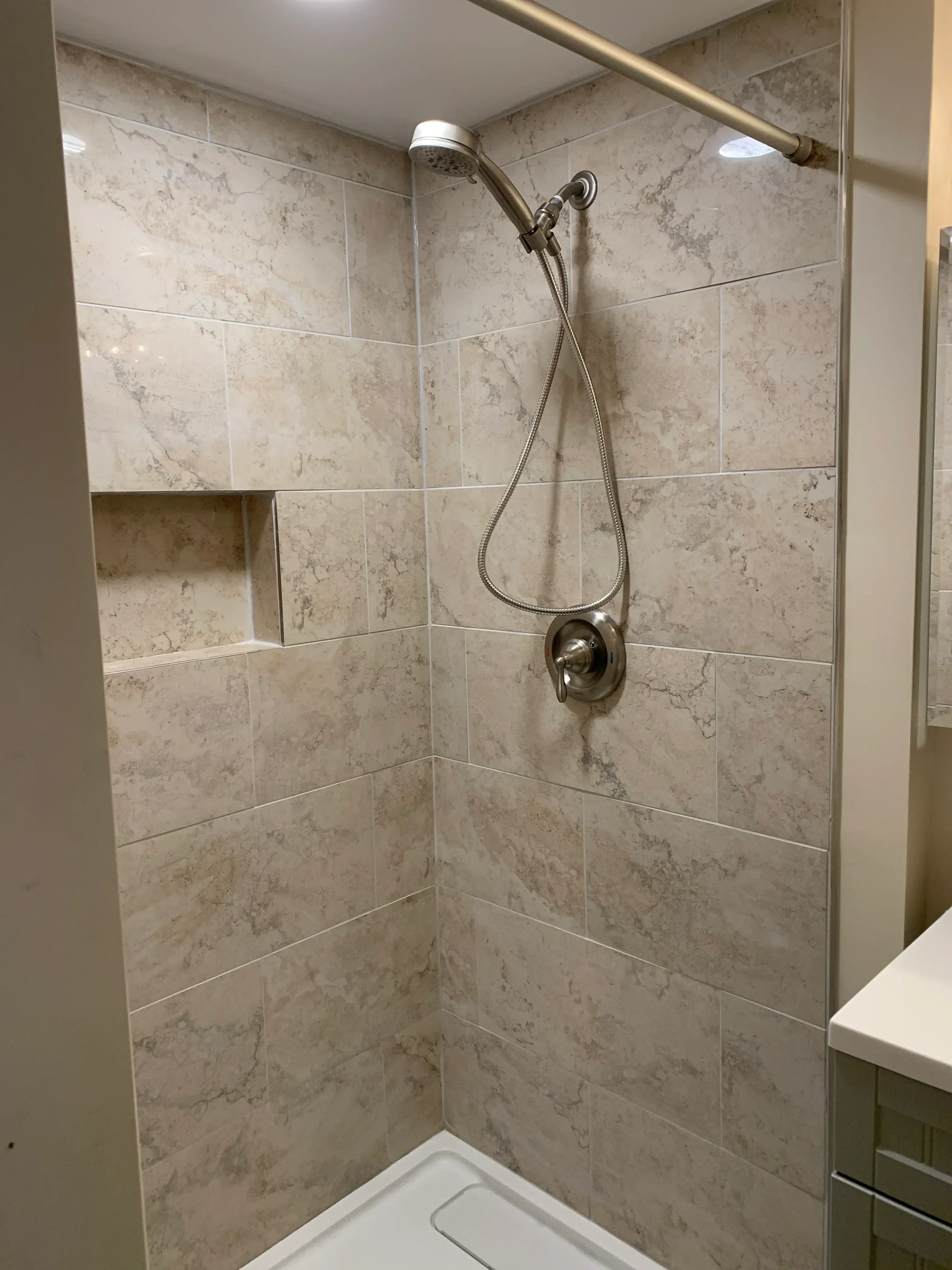 Marble-look ceramic tile shower with brushed nickel fixtures and rainfall showerhead