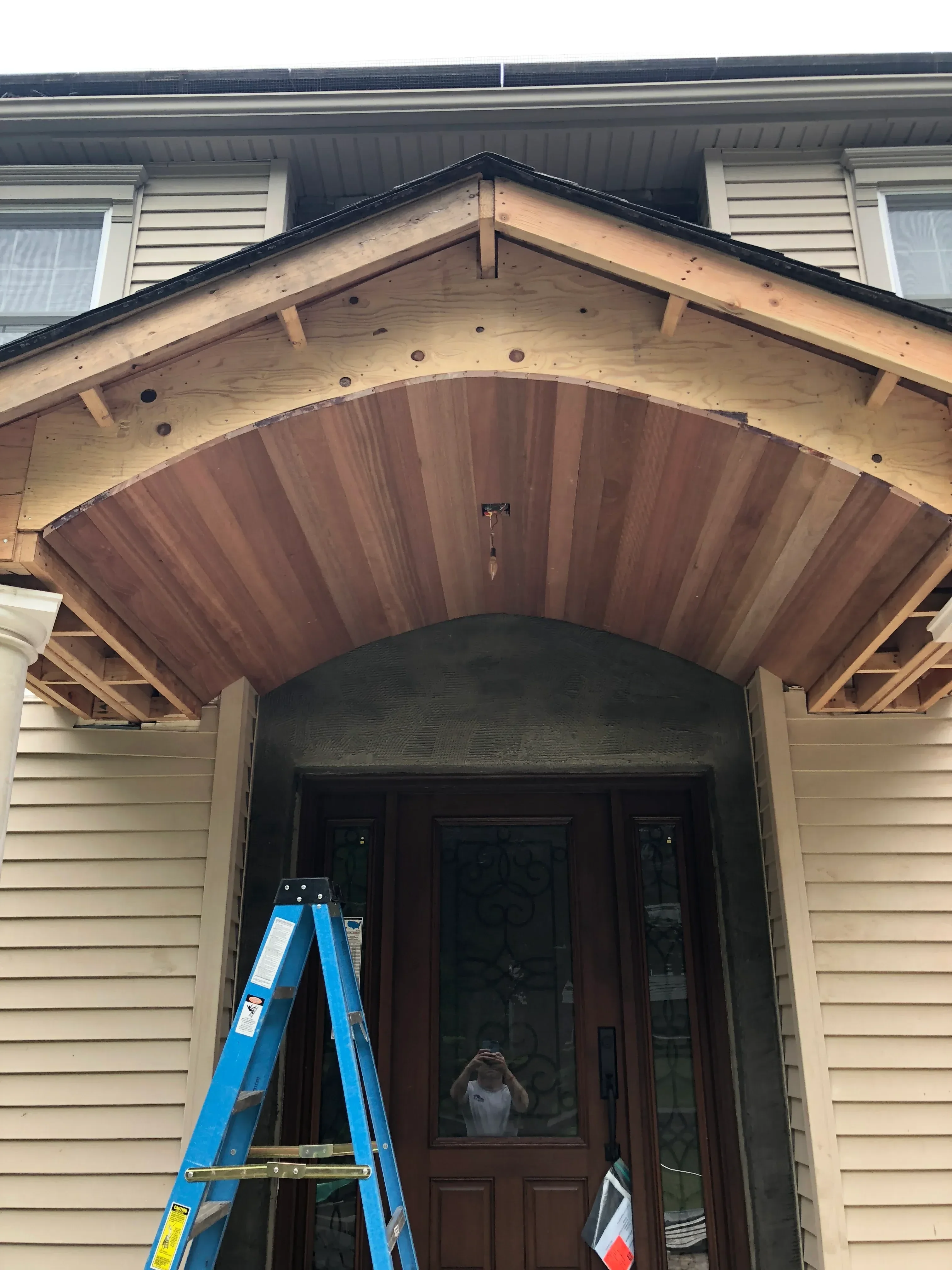 Custom wood garage door with horizontal cedar planks and timber frame during installation