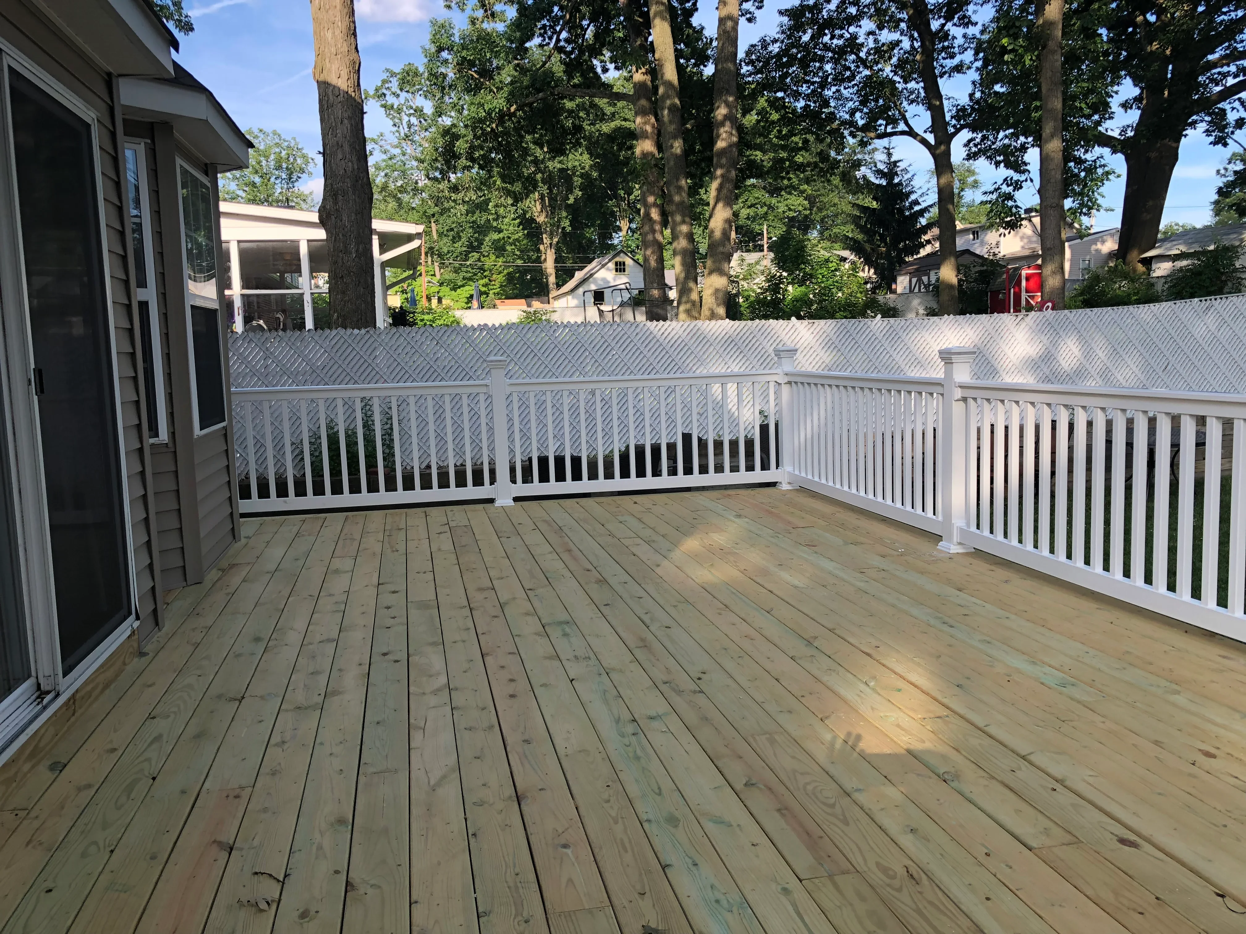 Composite deck with diagonal pattern decking and white vinyl railing overlooking wooded yard