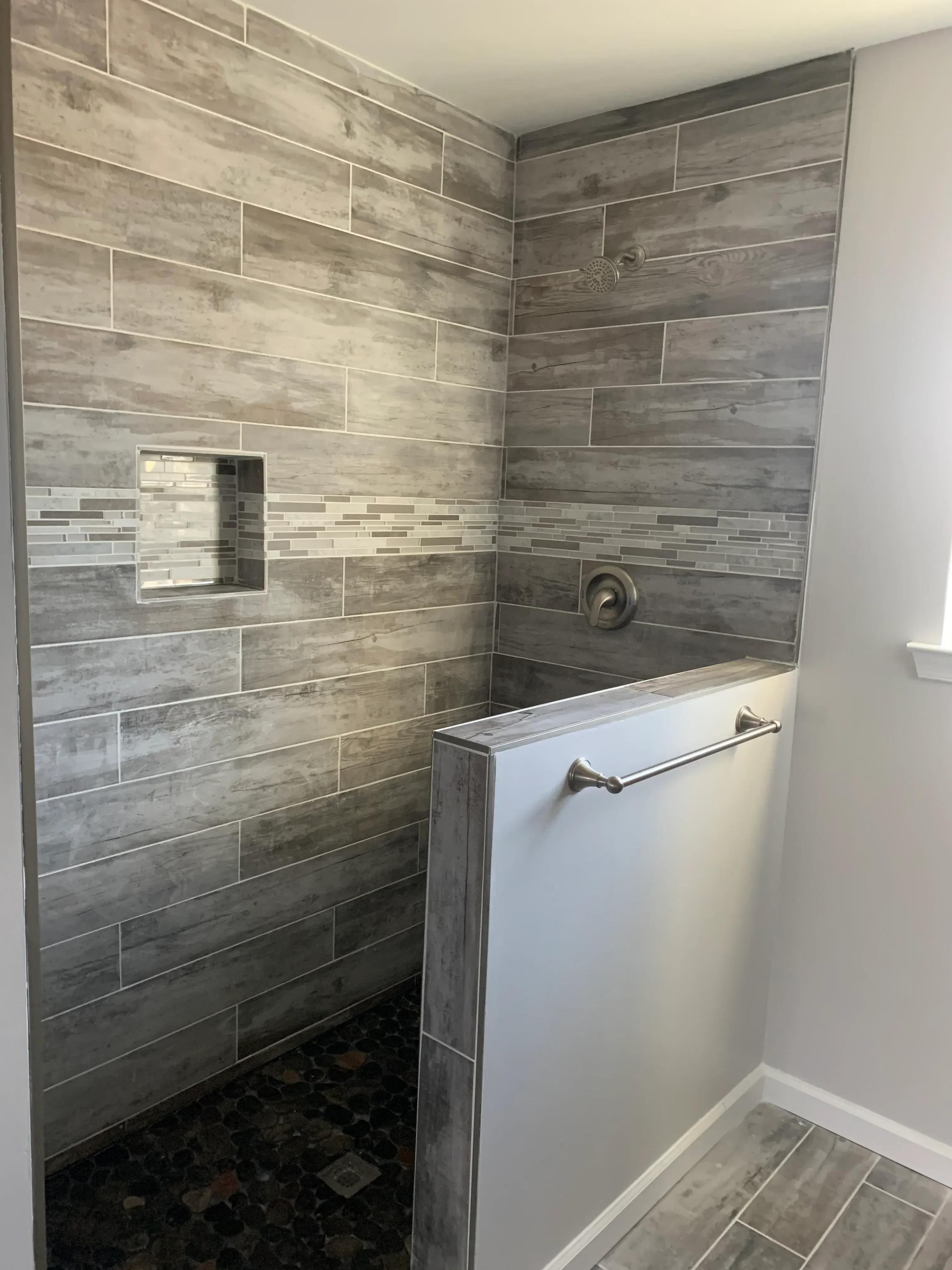 Gray wood-look porcelain tile shower with linear accent strips and brushed nickel fixtures