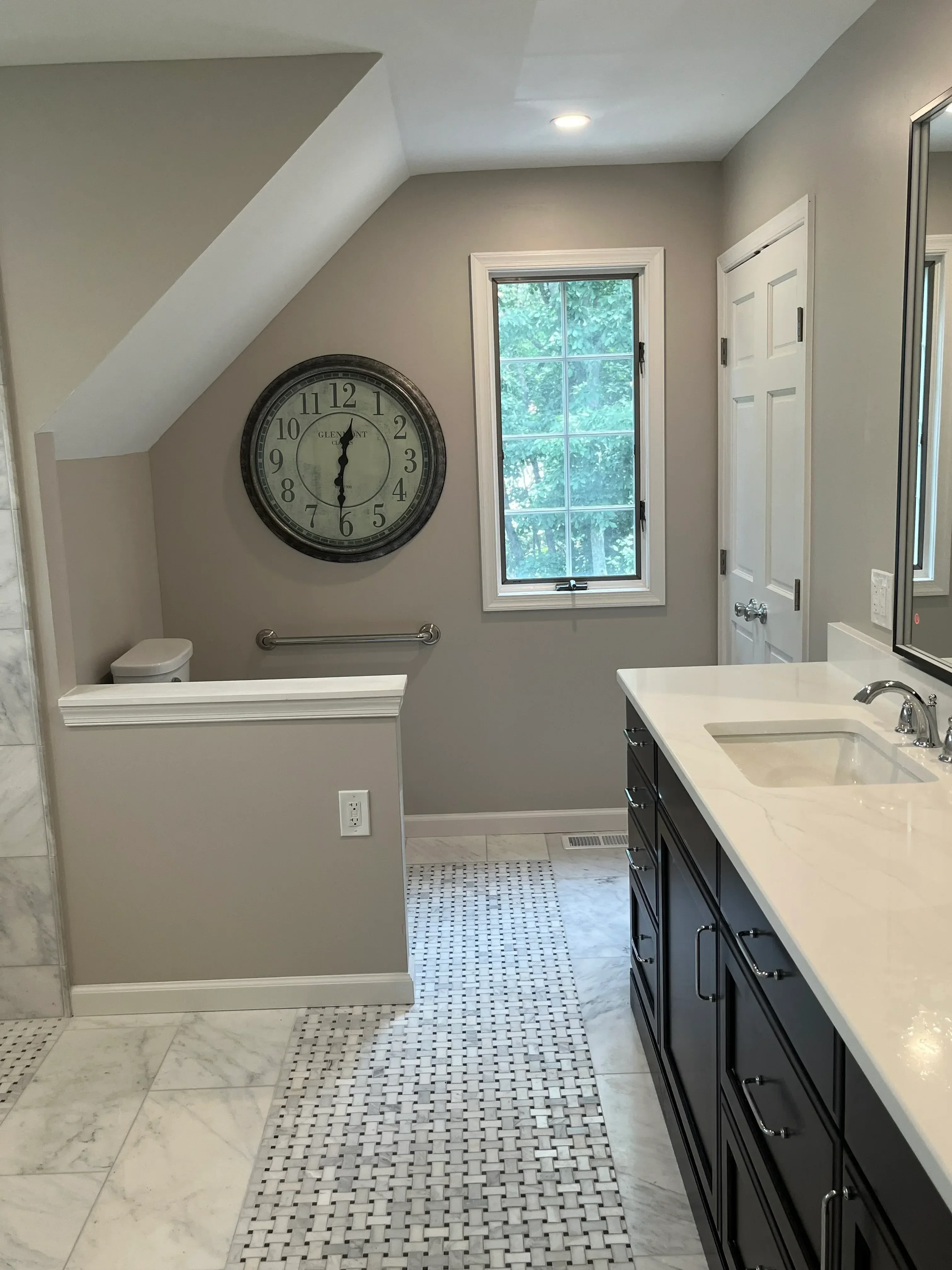 Kitchen with white cabinetry, geometric tile backsplash, marble flooring, and casement window