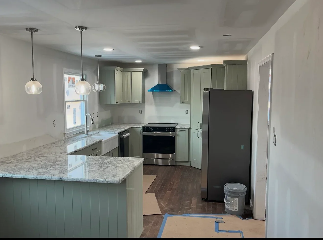 Kitchen with sage green cabinets, granite counters, stainless steel range, and pendant lights