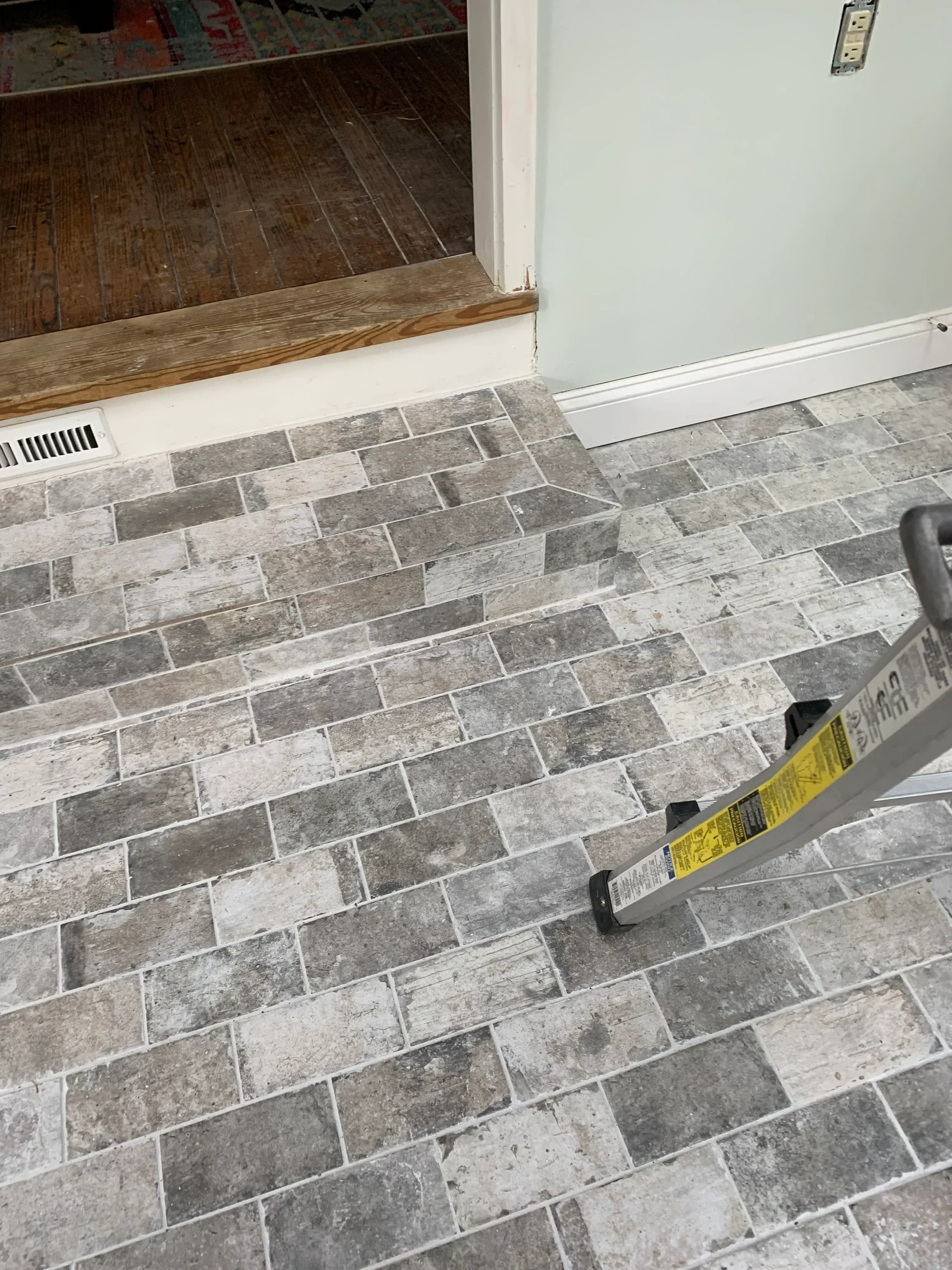 Gray porcelain tile floor in herringbone pattern with white grout lines