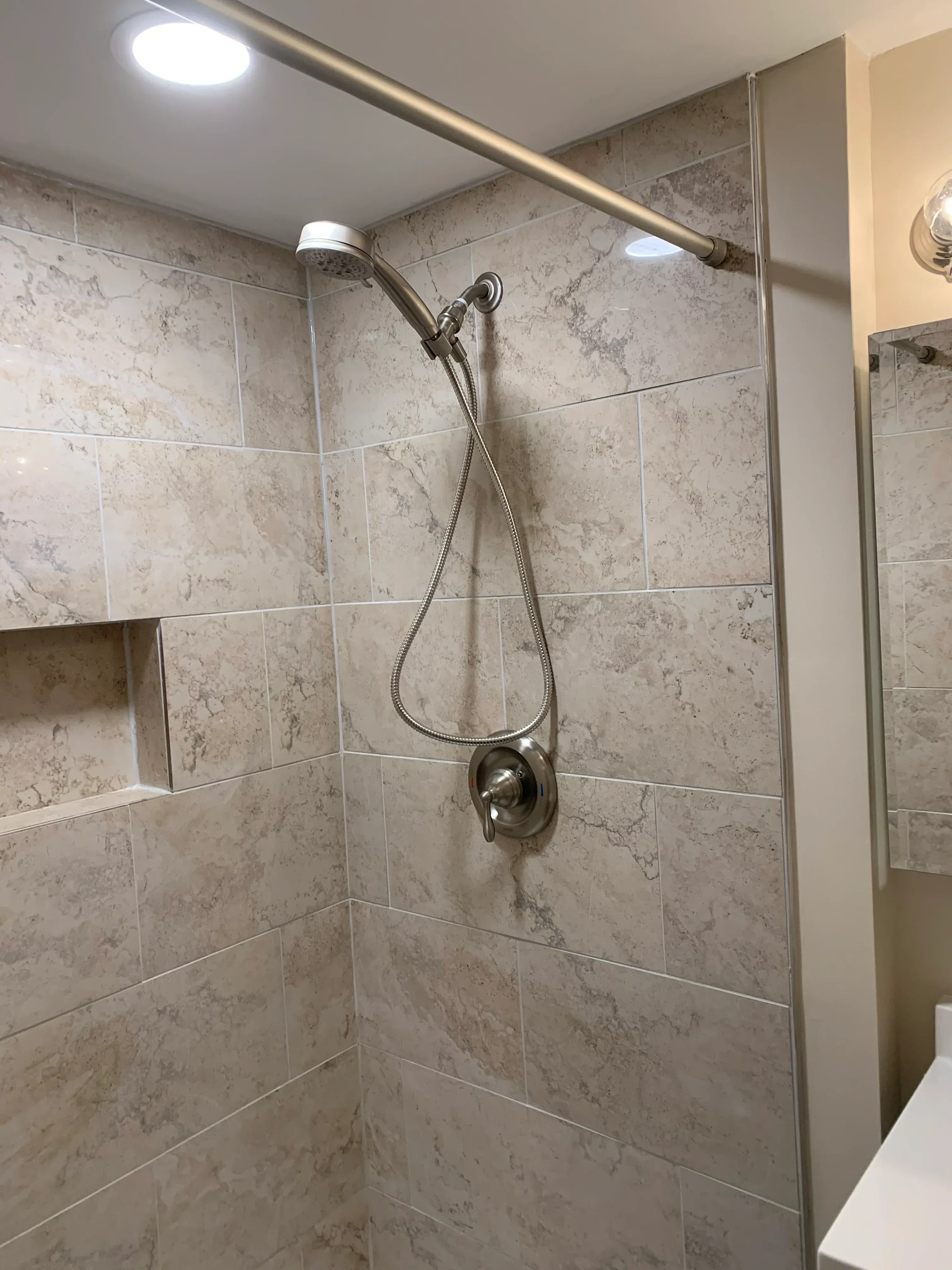 Travertine tile shower with dual showerheads and brushed nickel fixtures