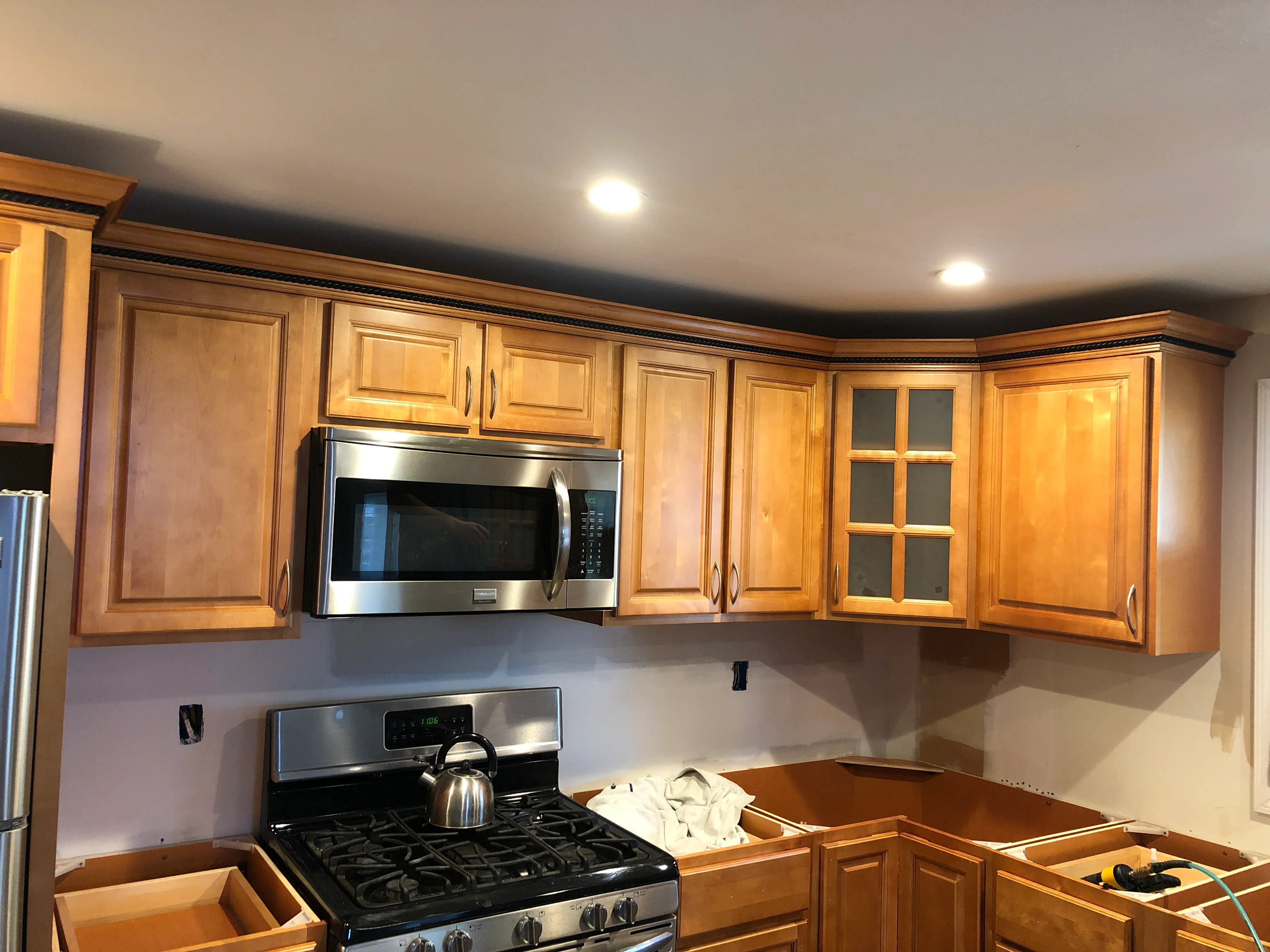 Kitchen with honey wood cabinetry, stainless steel gas range and microwave, recessed lighting