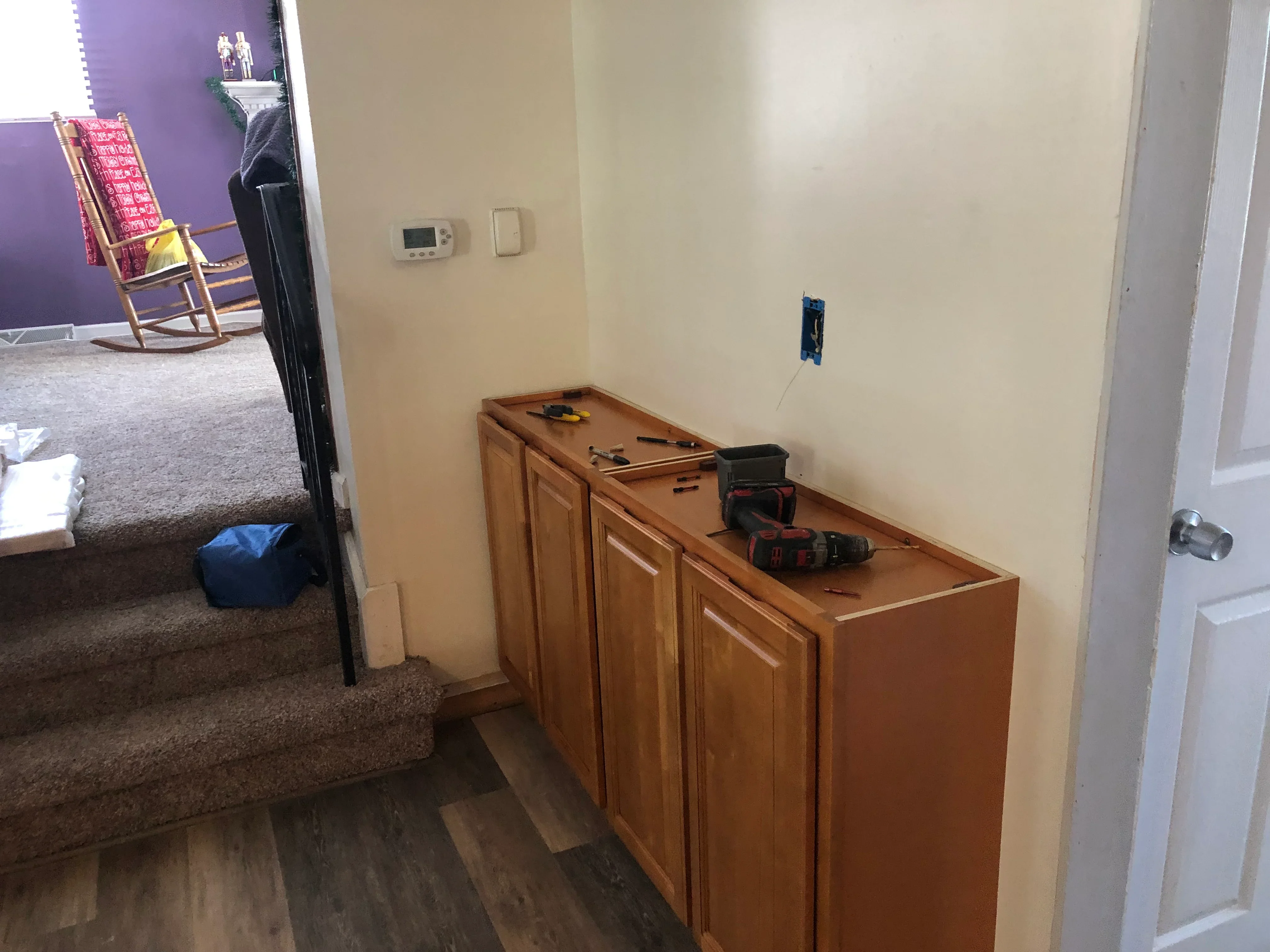 Wood base cabinets with raised panel doors and electrical outlet rough-in on cream drywall