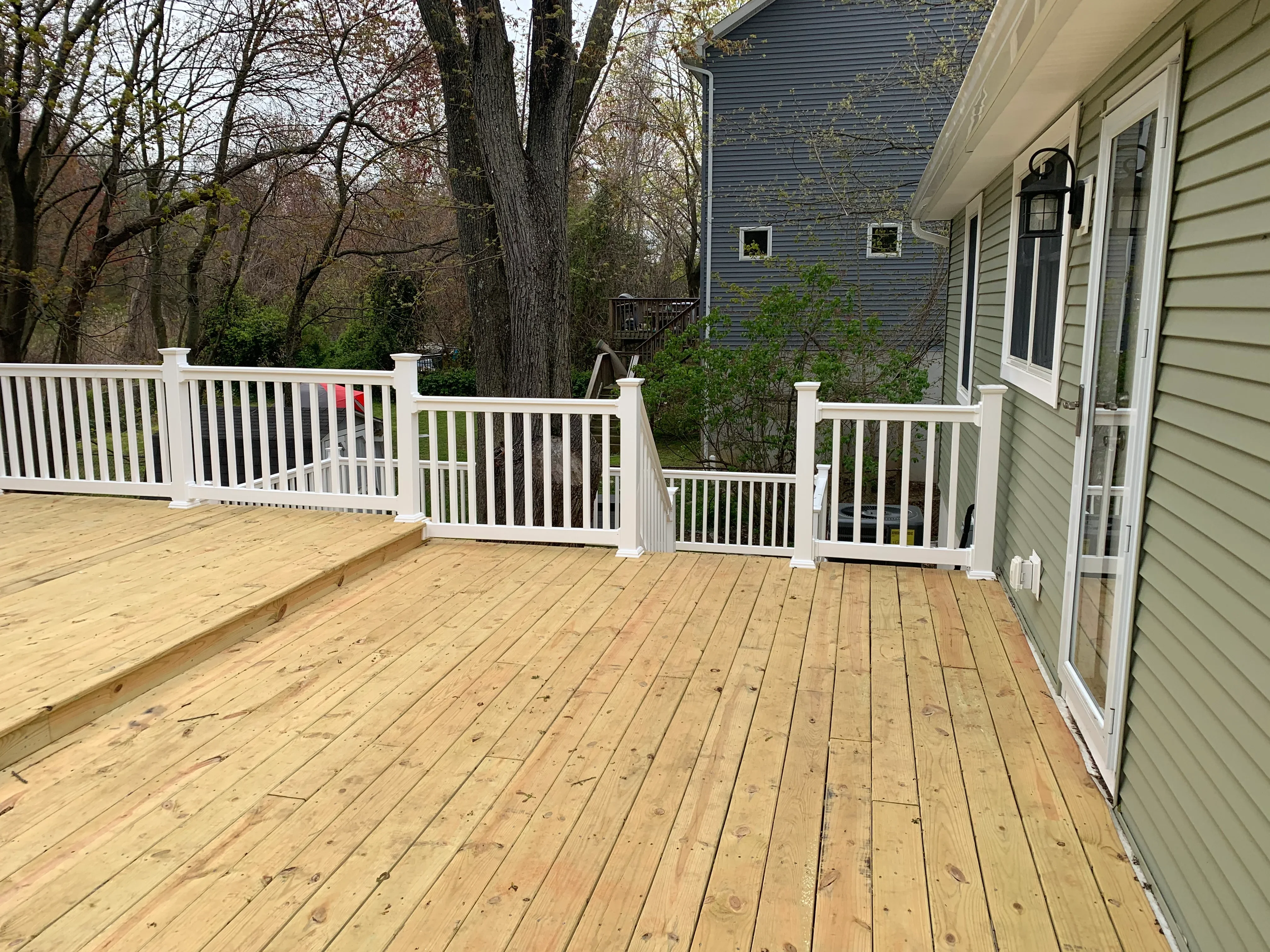Pressure-treated wood deck with white vinyl railings and gate installation