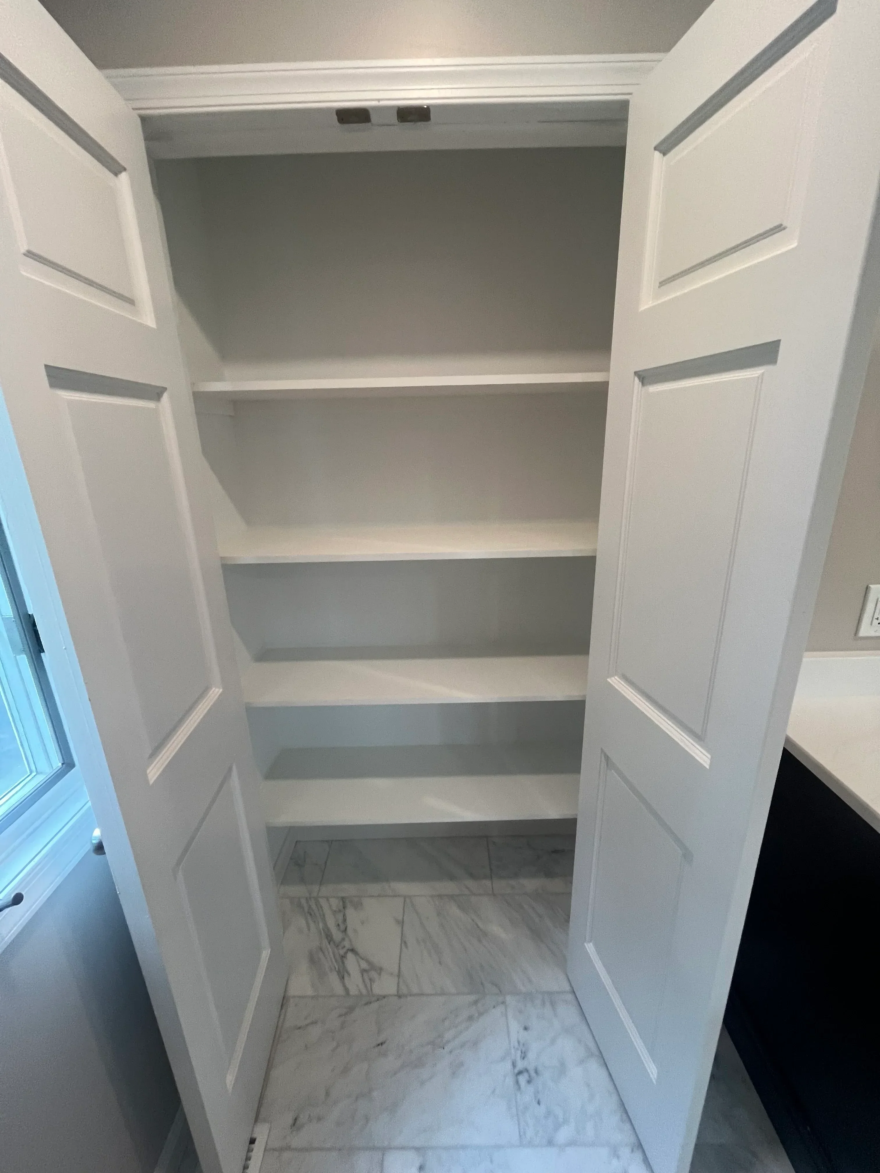 White built-in cabinetry with recessed shelves and marble tile backsplash installation