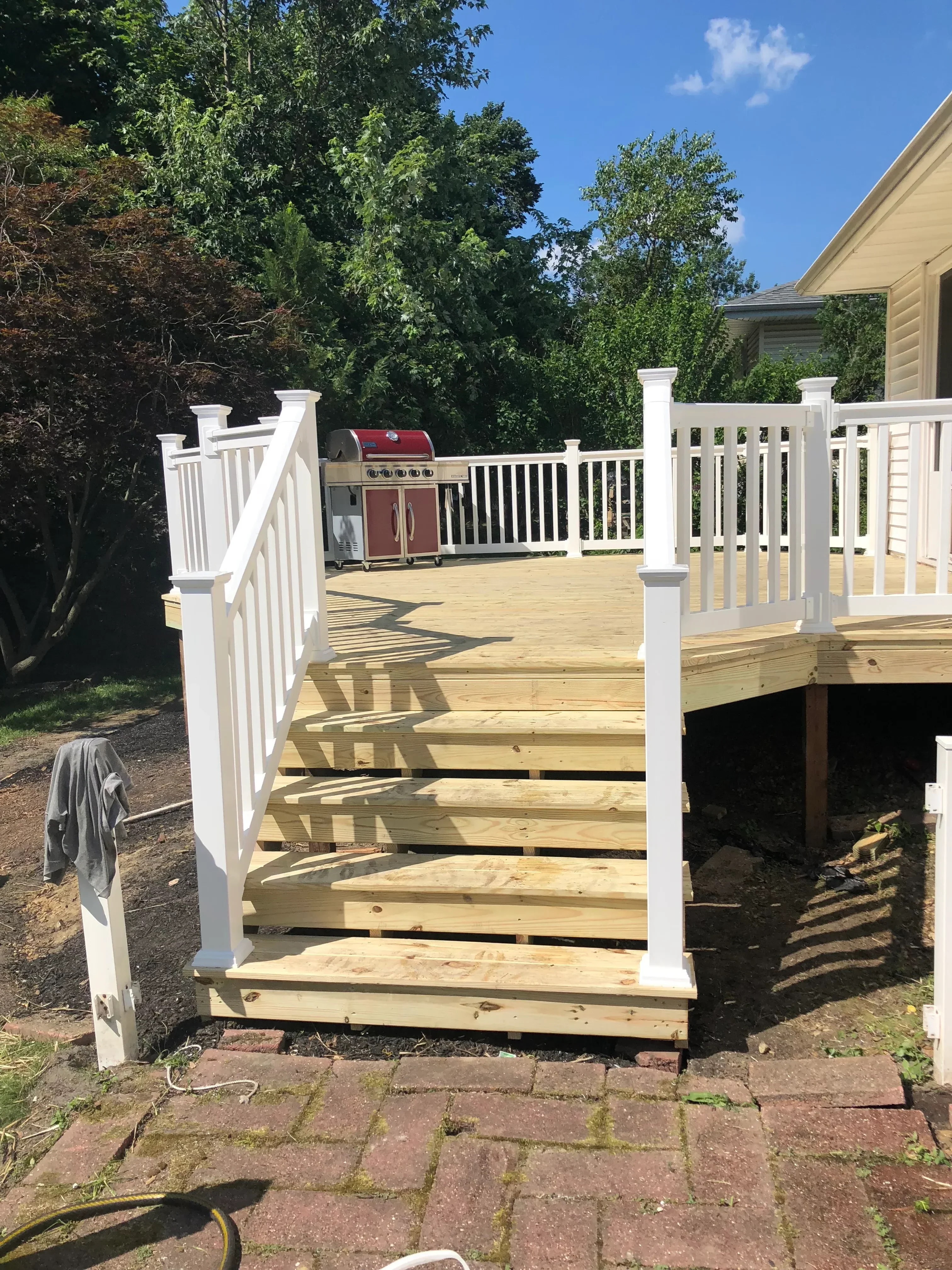 Pressure-treated wood deck with white vinyl railings and horizontal balusters under construction