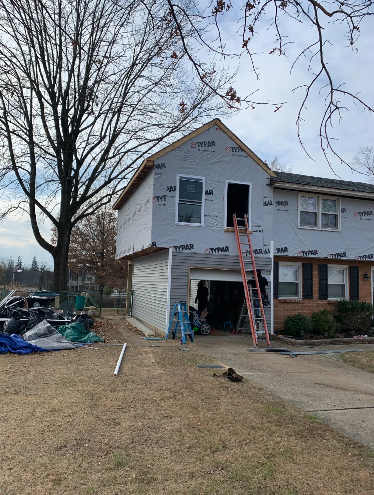 Two-story home addition with Tyvek wrap, new windows, and vinyl siding installation in progress