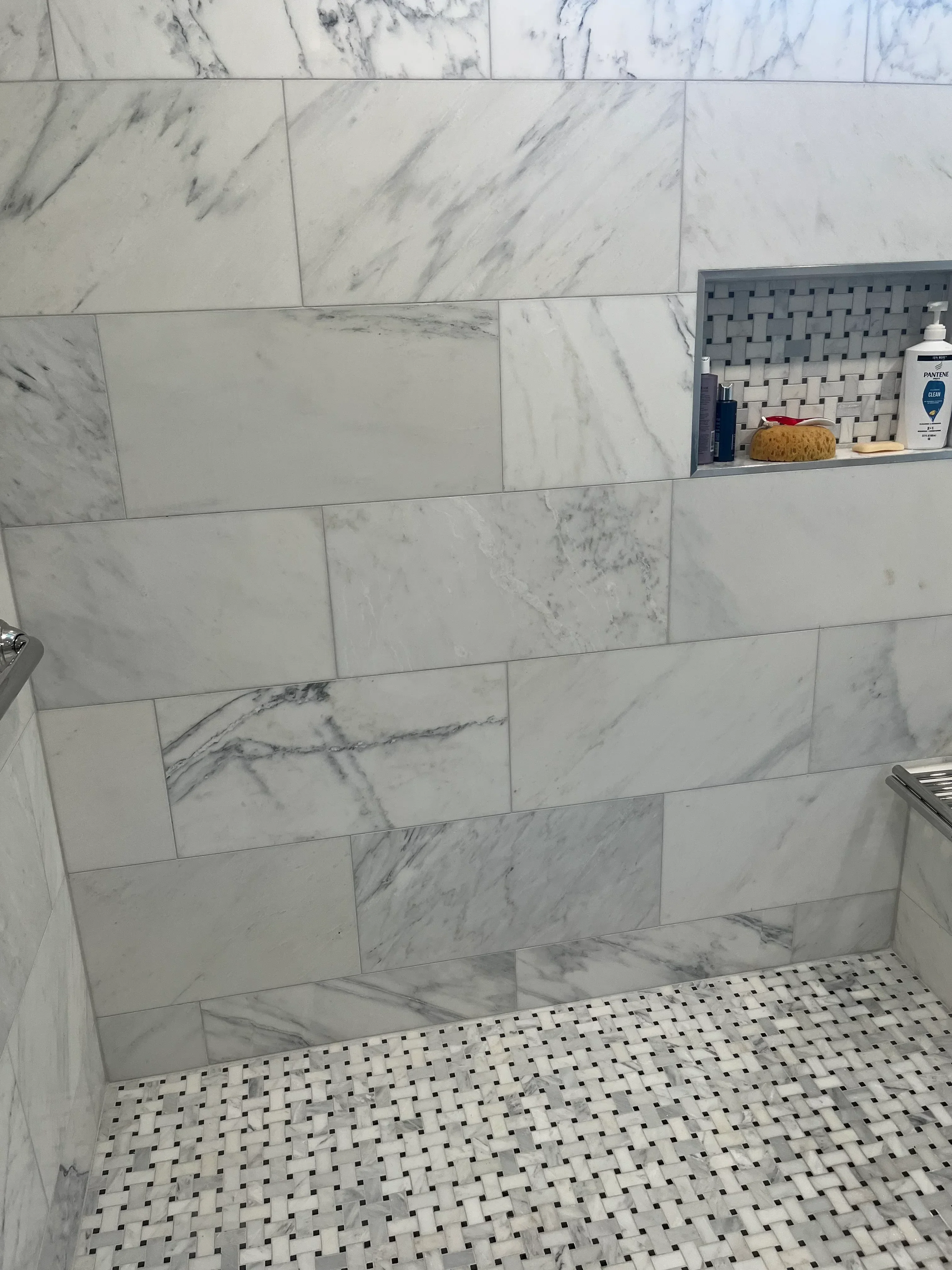 White and gray marble tile floor in running bond pattern with perforated metal accent wall