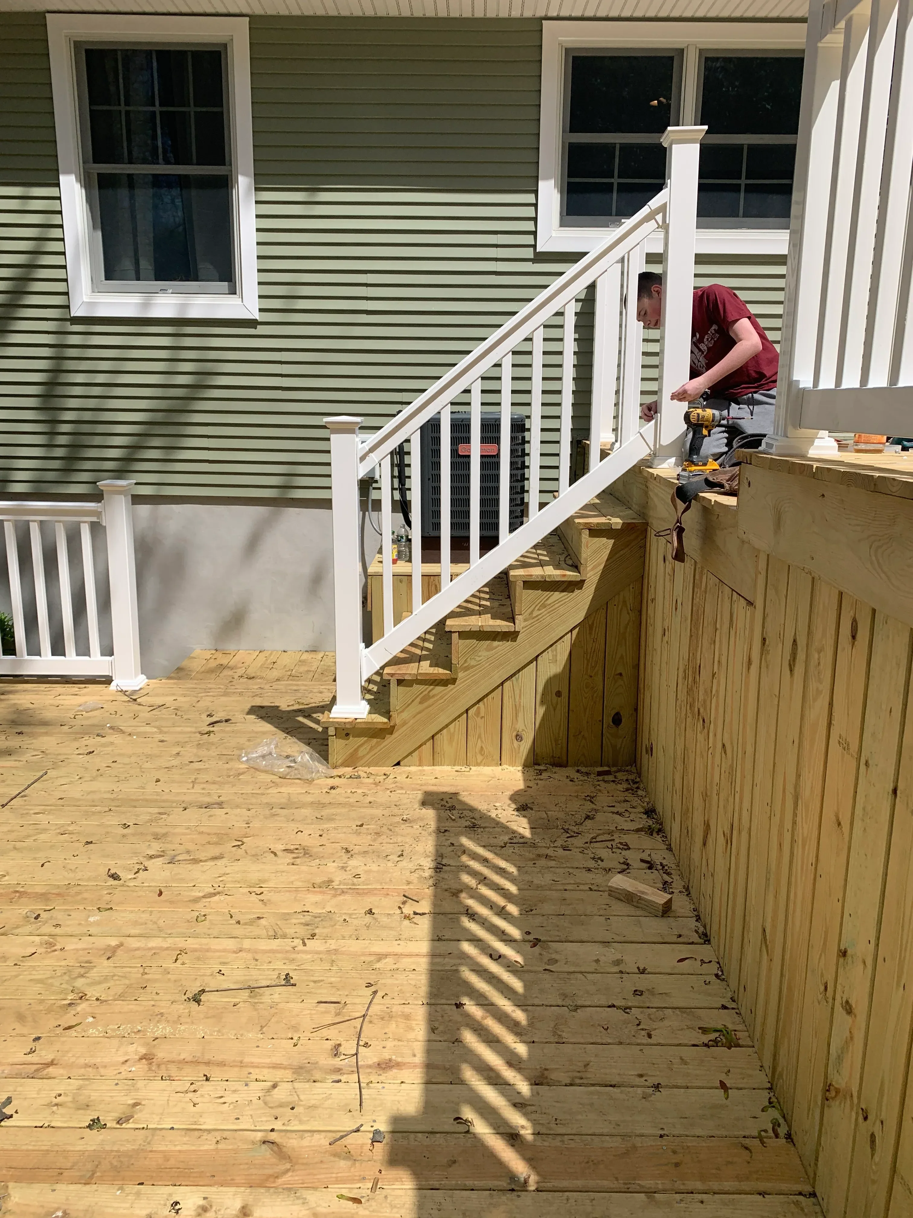 White aluminum deck railing and stairs with pressure-treated lumber framing during construction