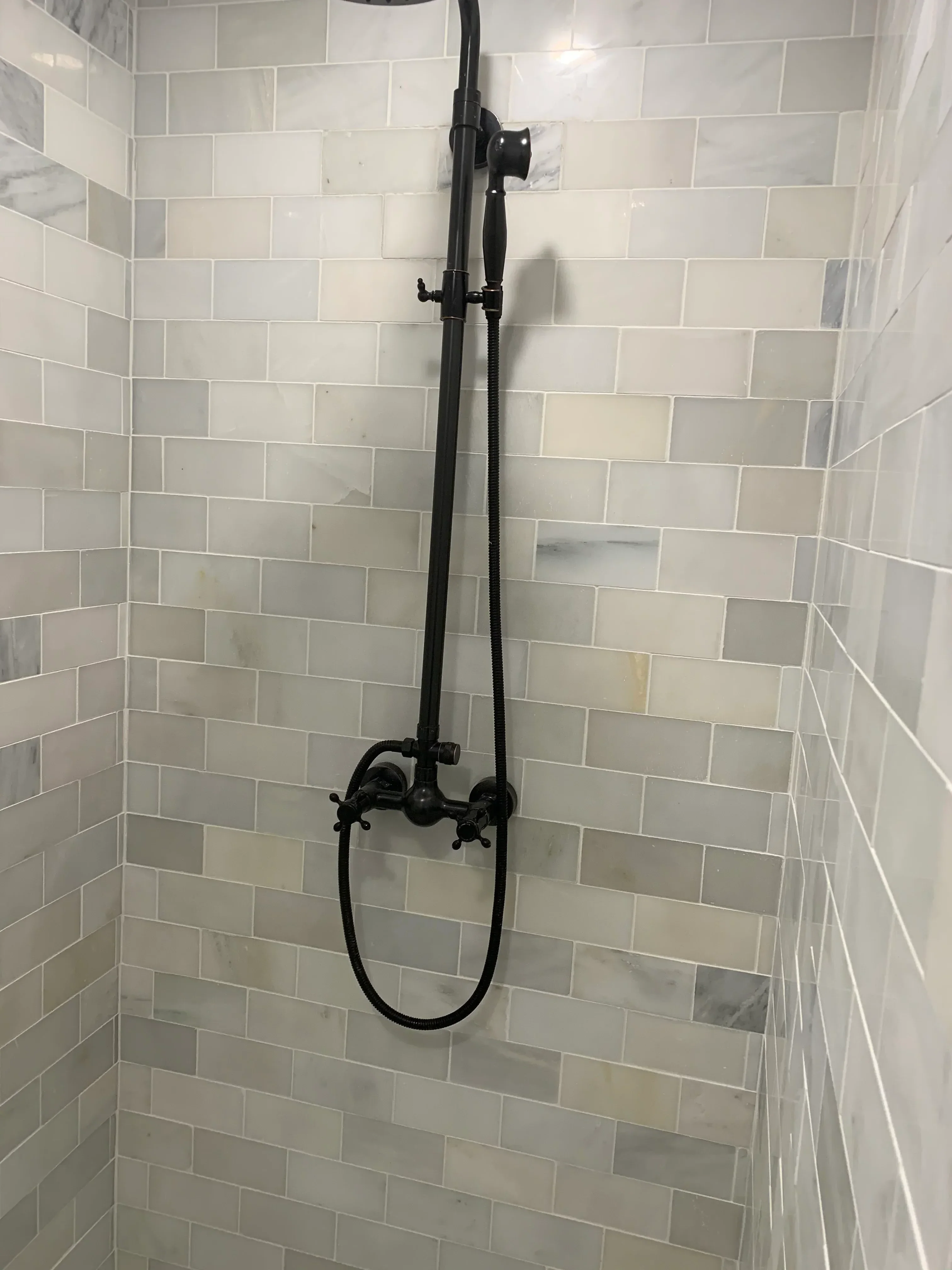 Staggered subway tile bathroom wall with black towel bar and recessed lighting